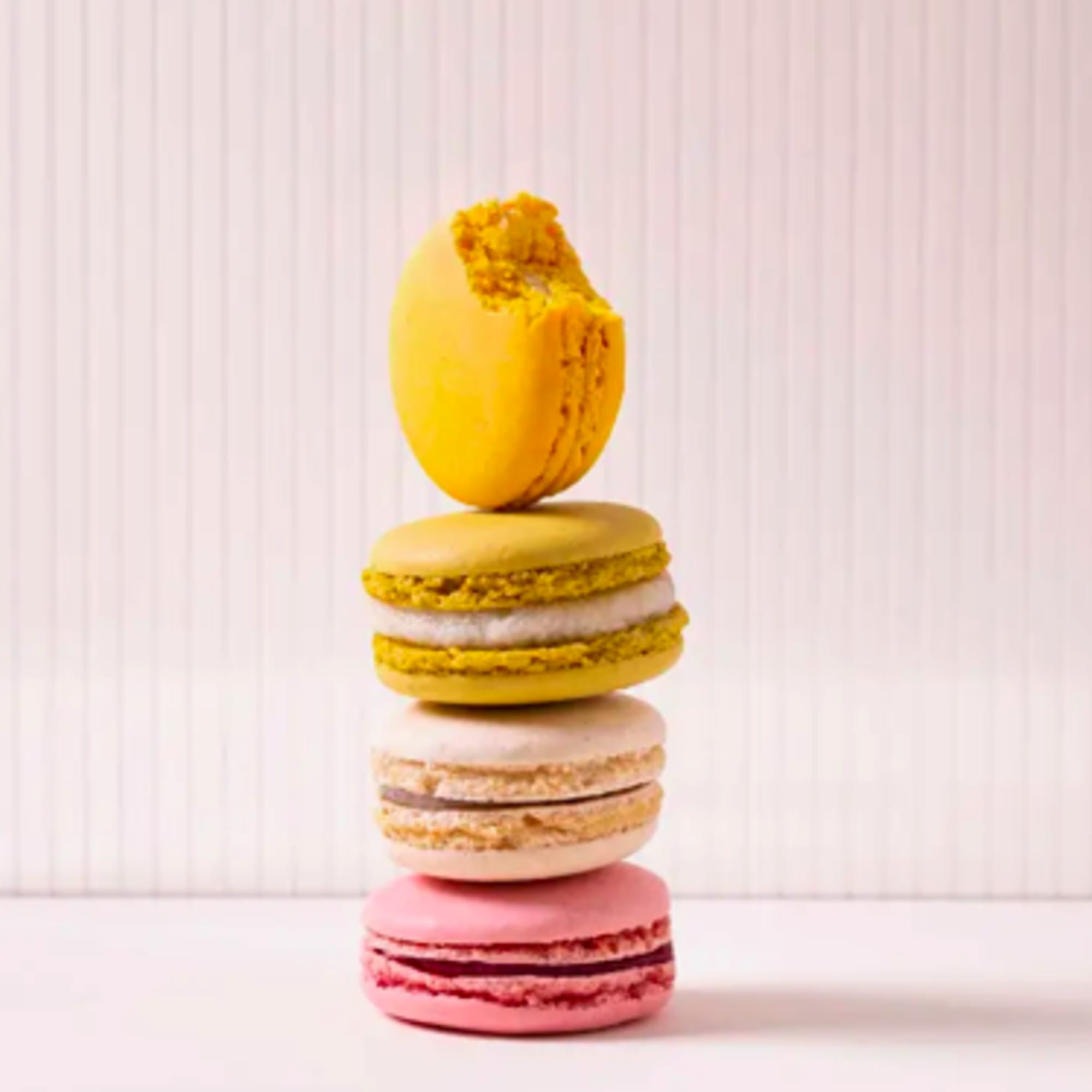 Stack of colorful macarons with one bitten yellow macaron on top