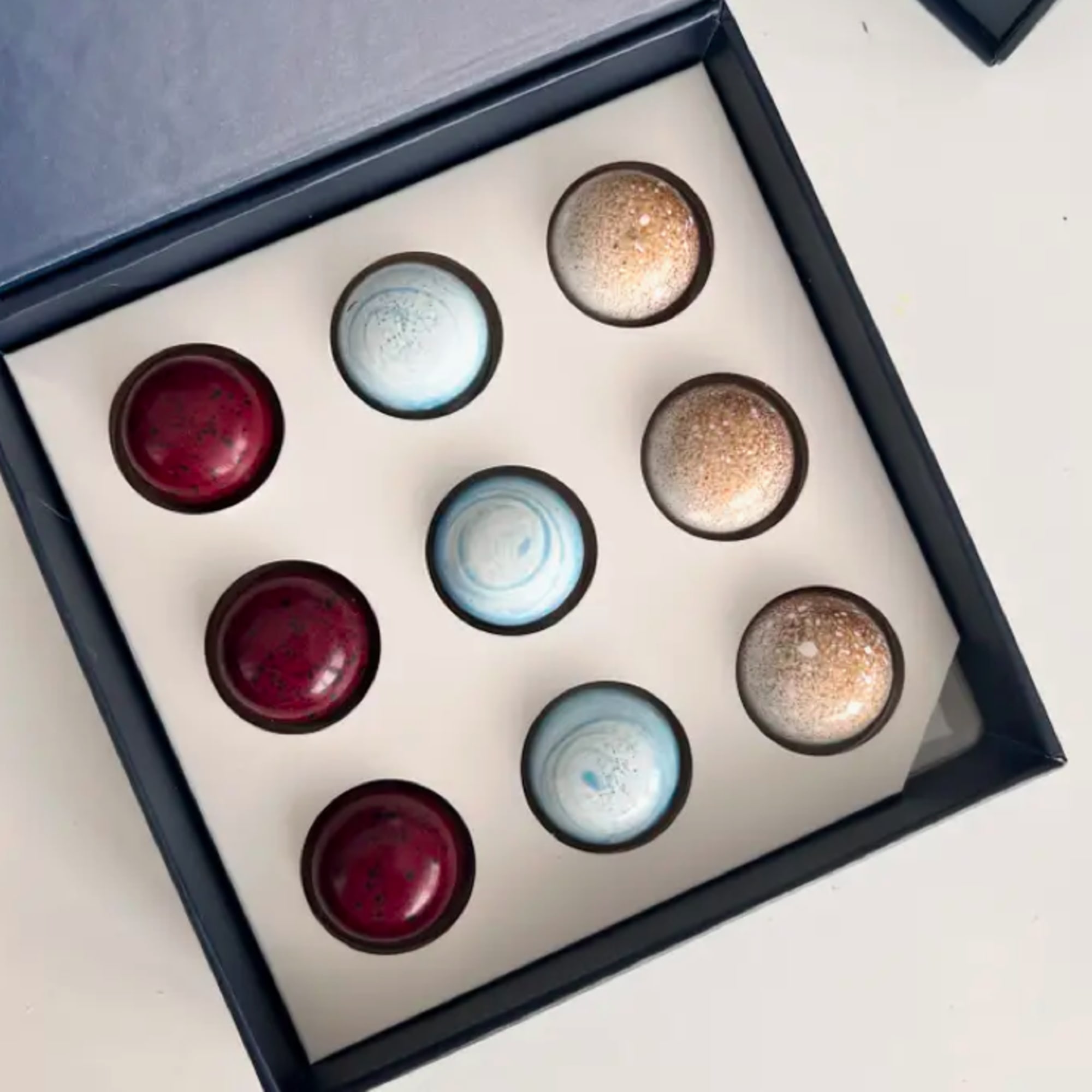Box of assorted round chocolates in red, blue, and gold
