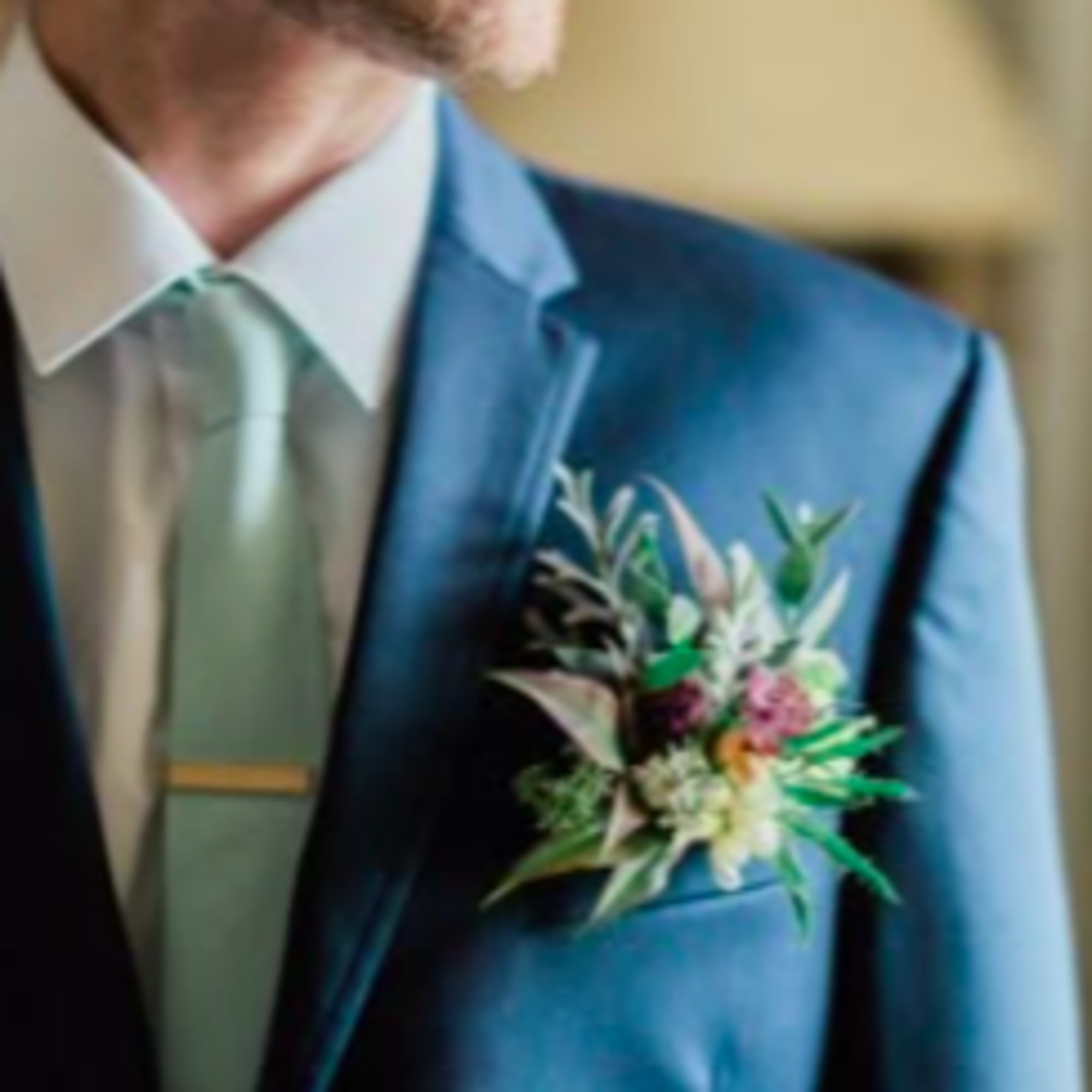 Boutonniere with small mixed flowers pinned to a blue suit jacket