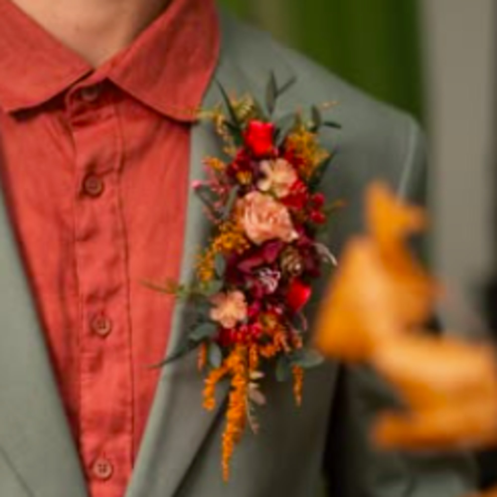Boutonniere with red and peach flowers on a suit jacket
