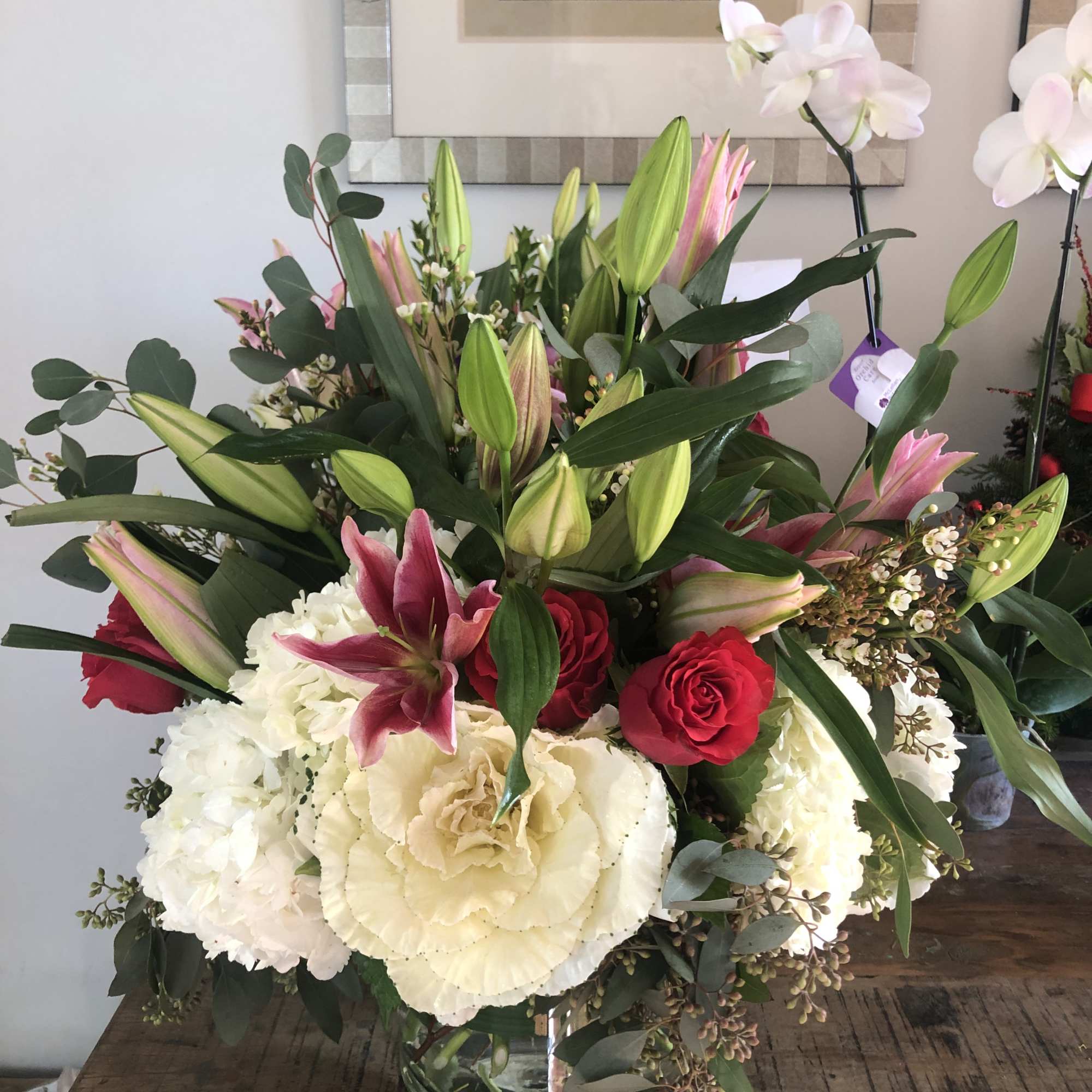 Mixed bouquet of lilies, roses, and white hydrangeas in a glass vase