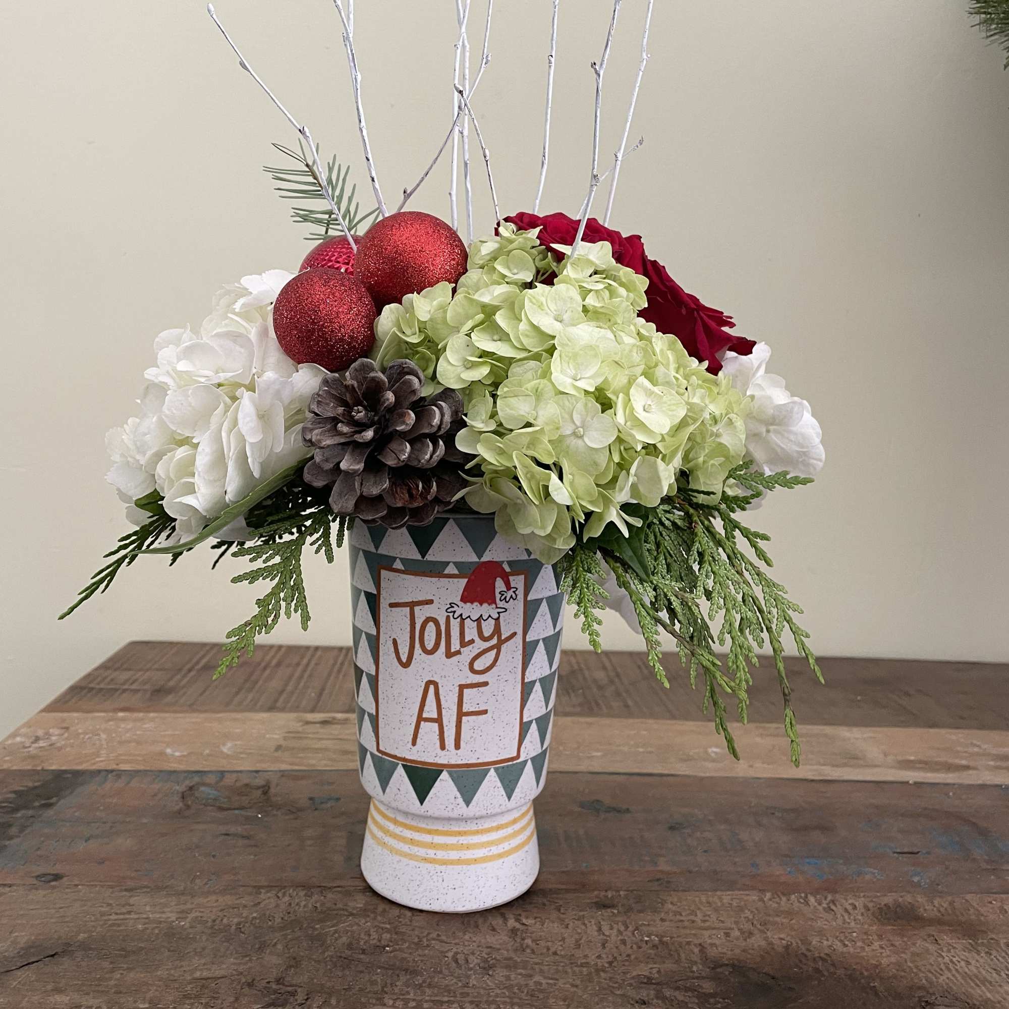 Holiday arrangement in a decorative vase with hydrangeas, roses, and ornaments