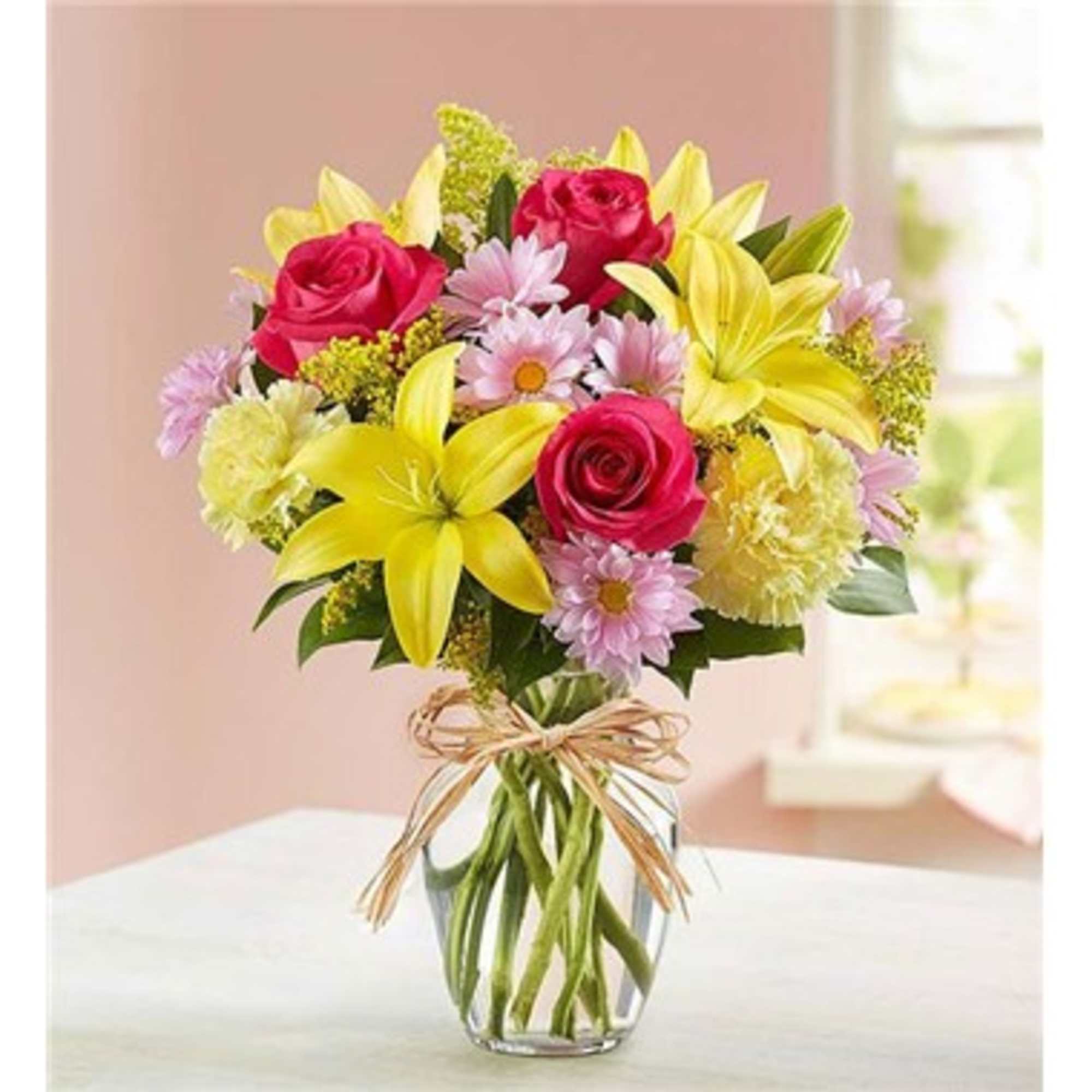 Bouquet of pink roses and yellow lilies in a clear glass vase