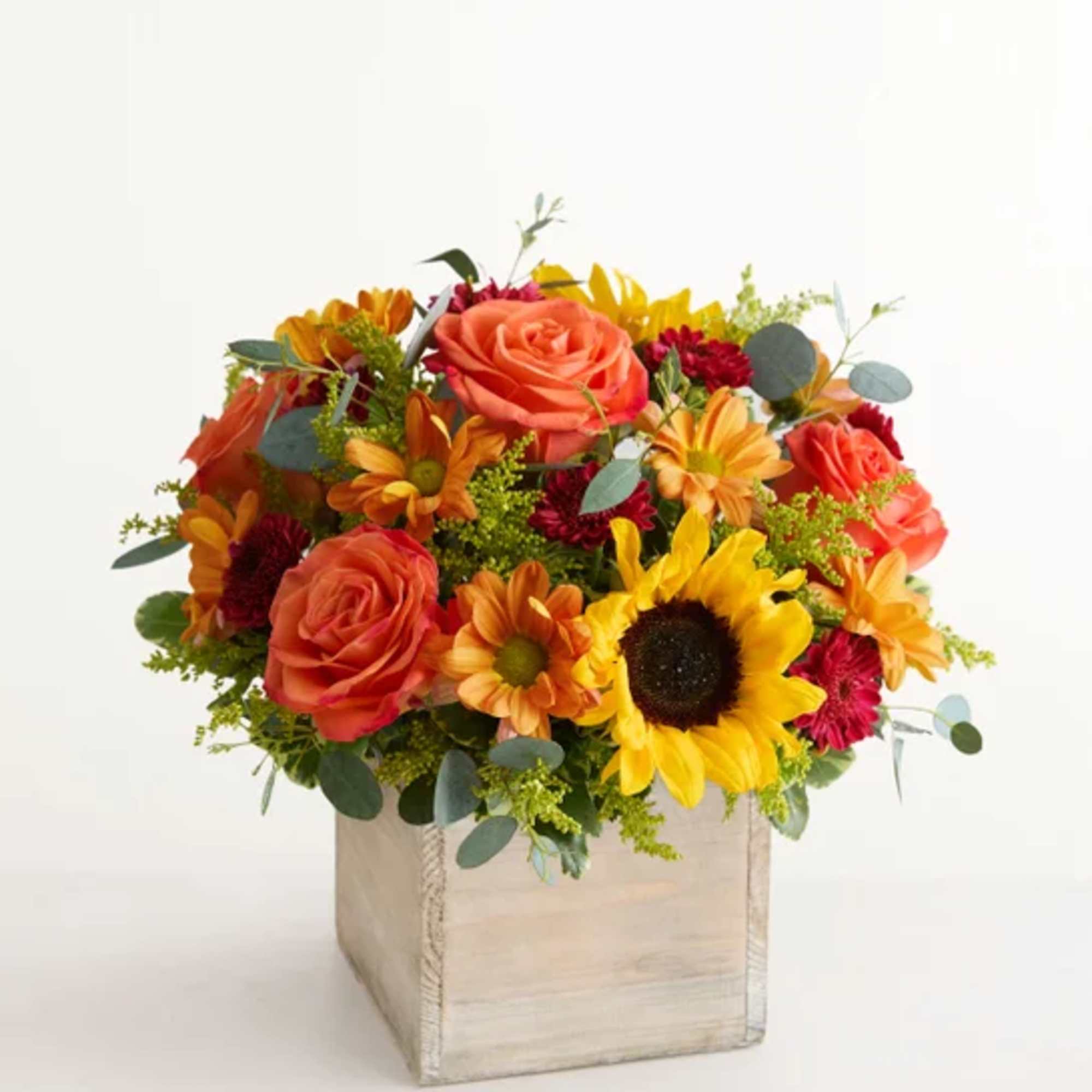 Bouquet of orange roses, sunflowers, and daisies in a wooden box