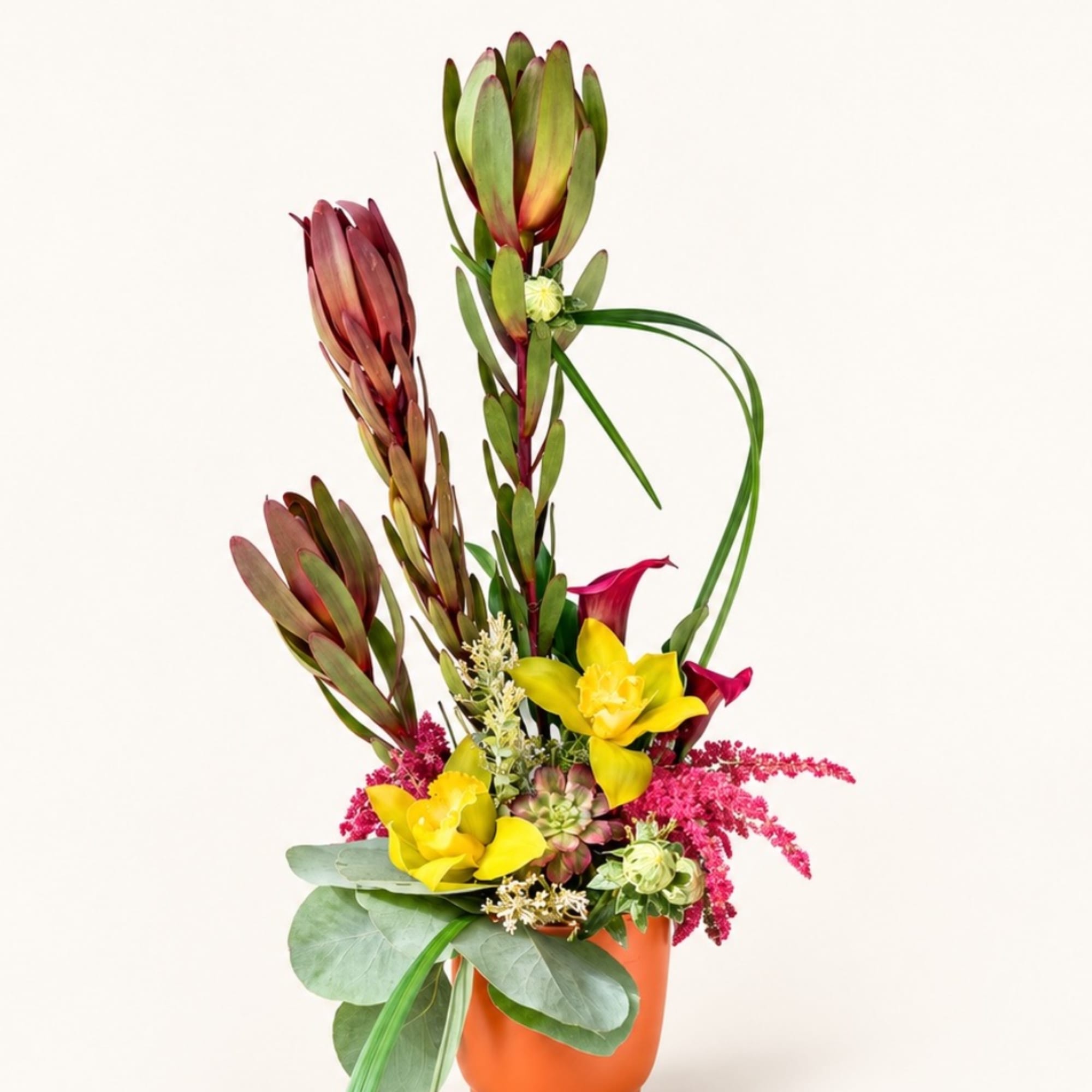 Tall tropical flower arrangement in an orange vase with yellow blooms