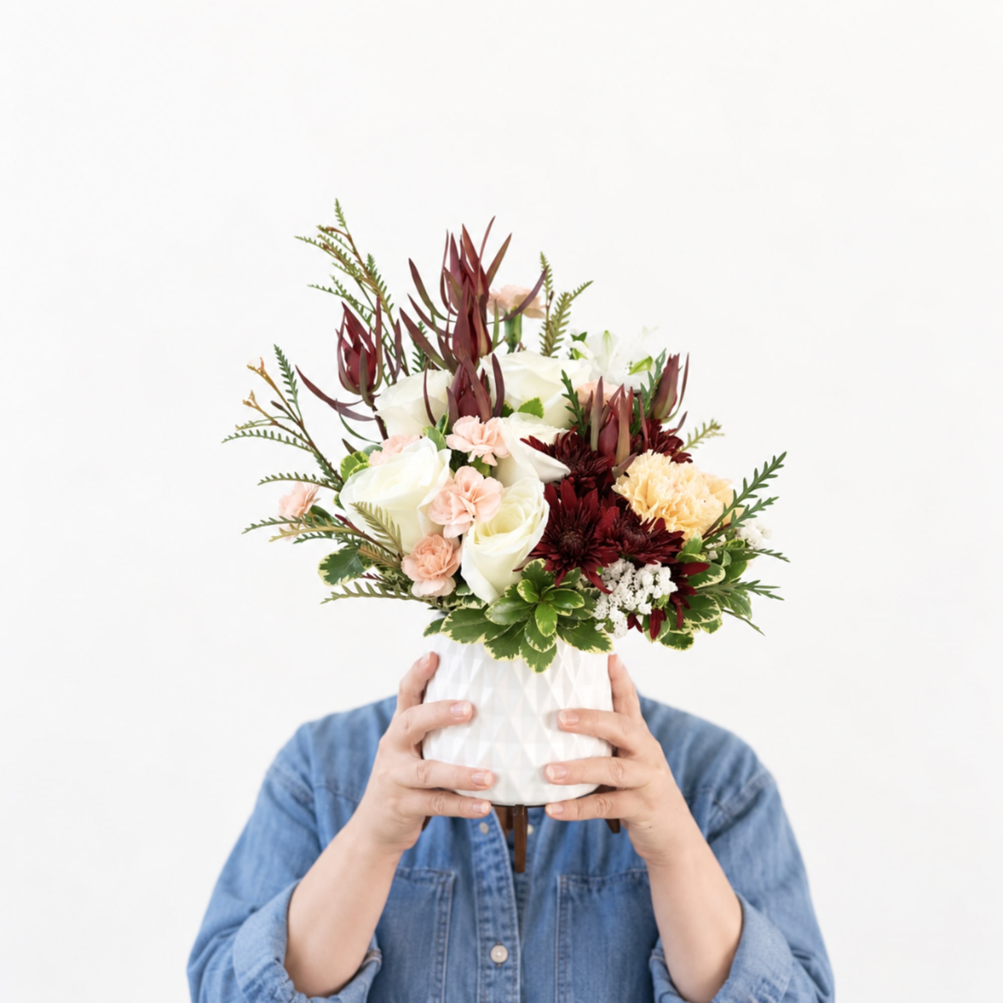 Mixed bouquet in a white vase with white, blush, and burgundy flowers