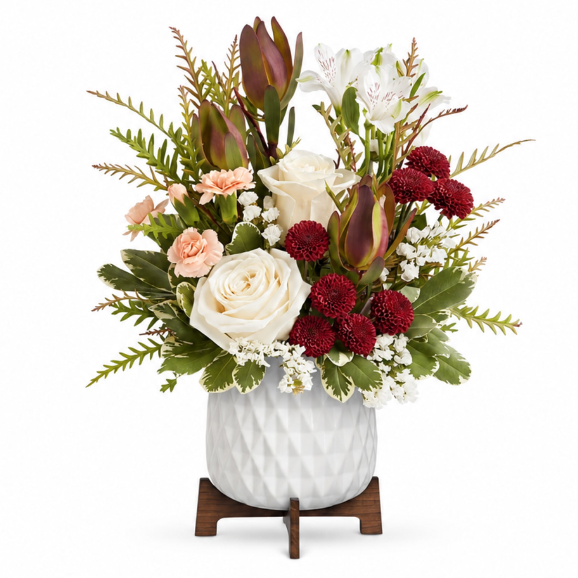White roses and red blooms arranged in a white vase