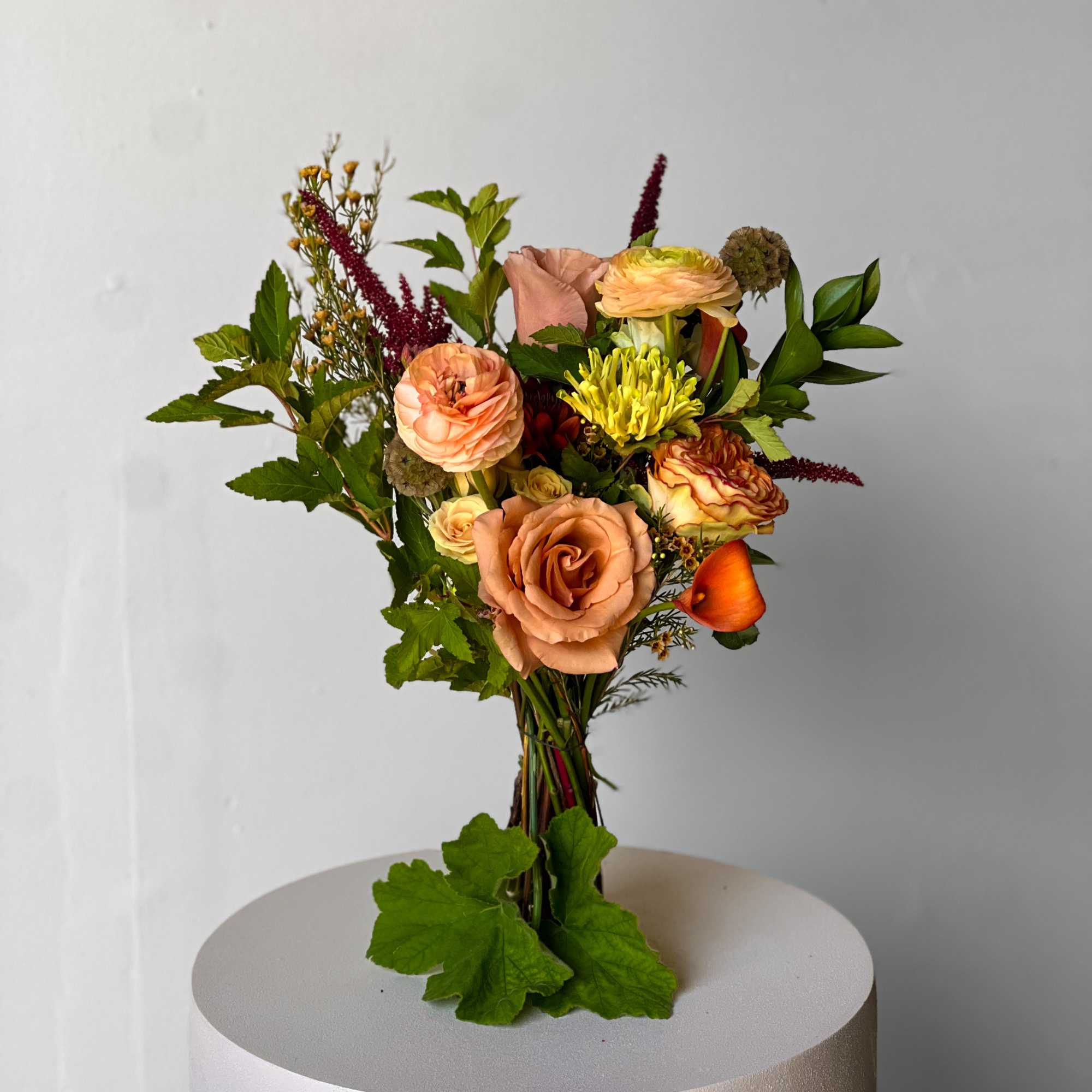 Mixed bouquet of peach and yellow flowers with greenery