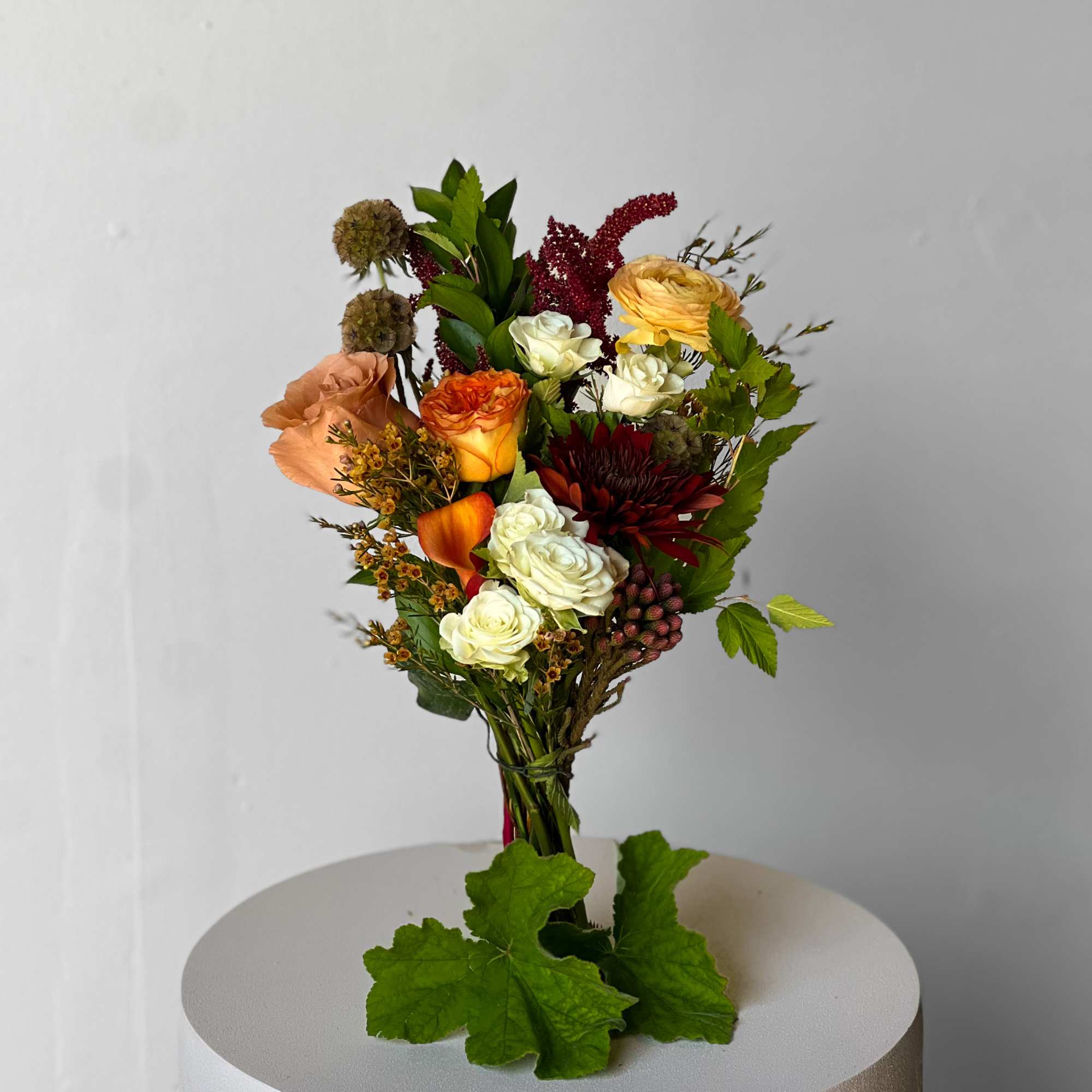 Mixed bouquet with roses, calla lilies, and greenery on a pedestal