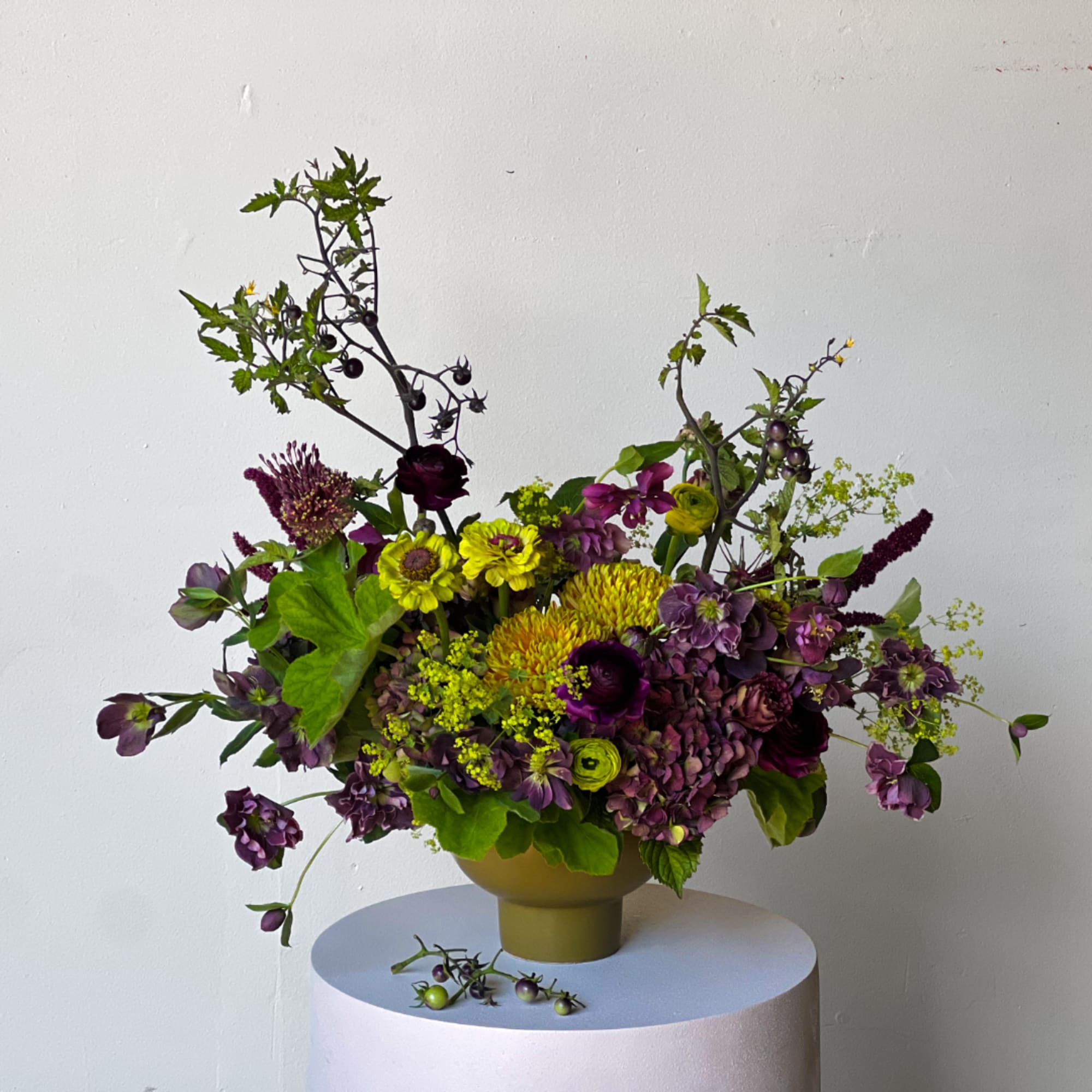 Purple and yellow floral arrangement in a gold vase