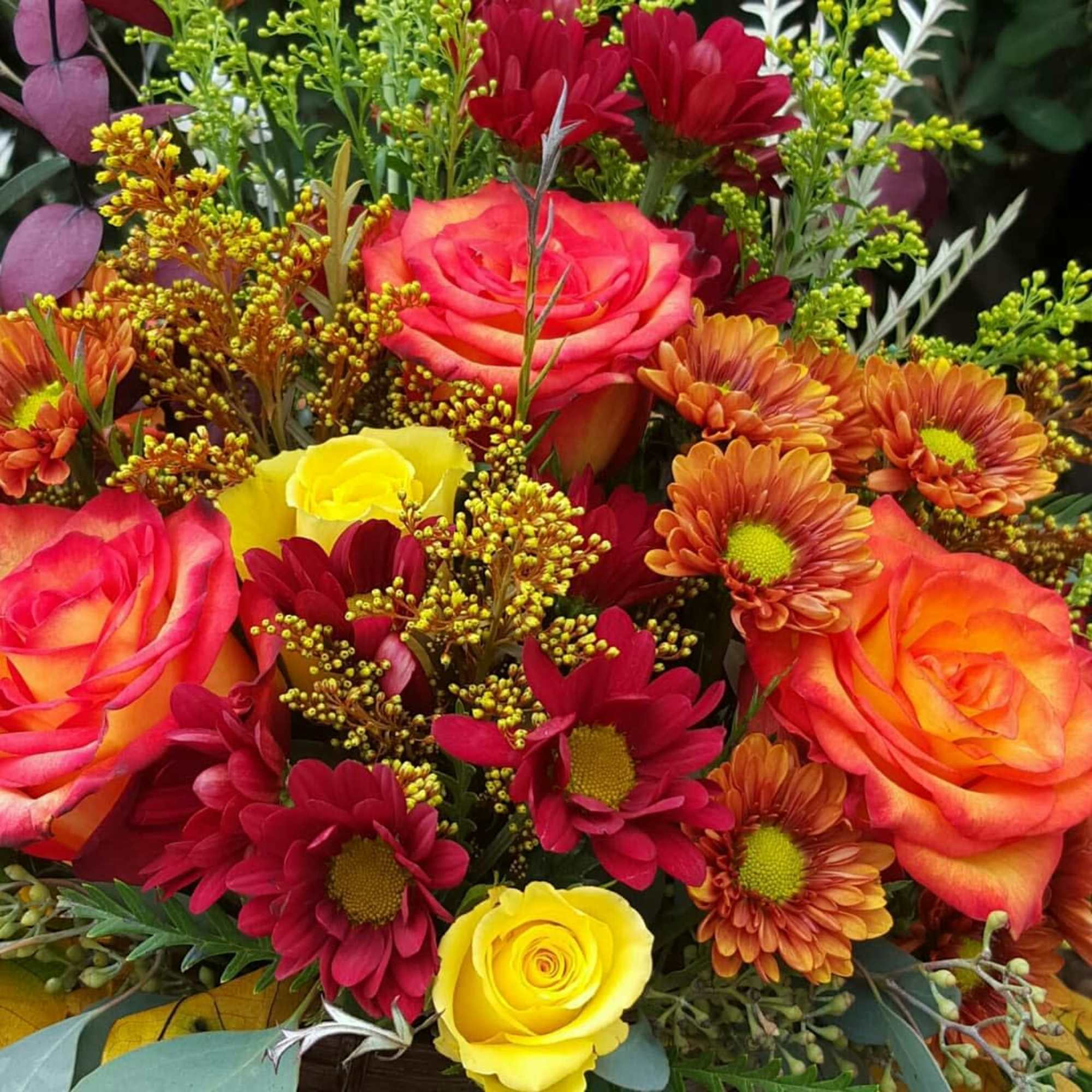 Colorful bouquet of roses and daisies with mixed greenery