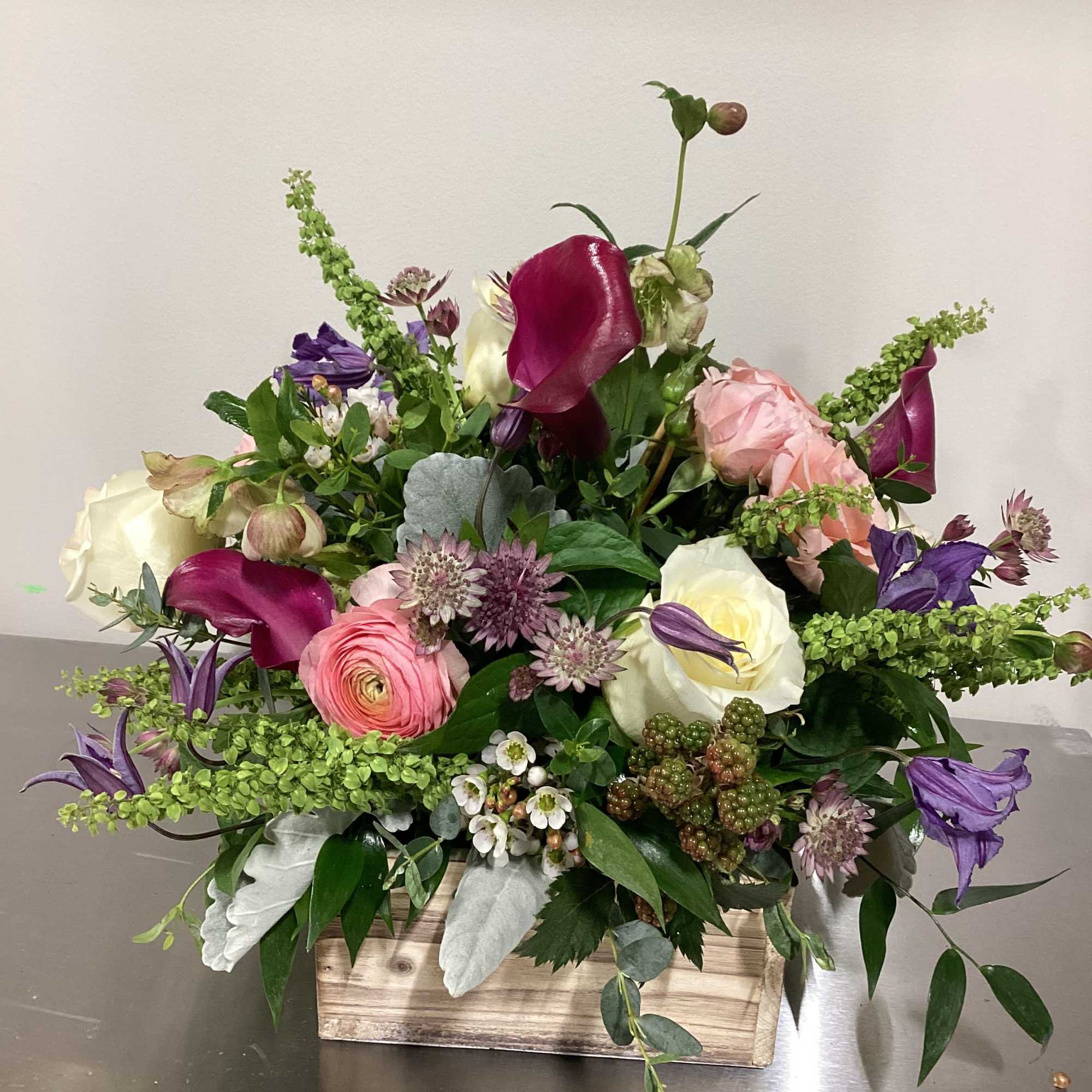 Mixed floral arrangement in a wooden box with pink, white, and purple blooms