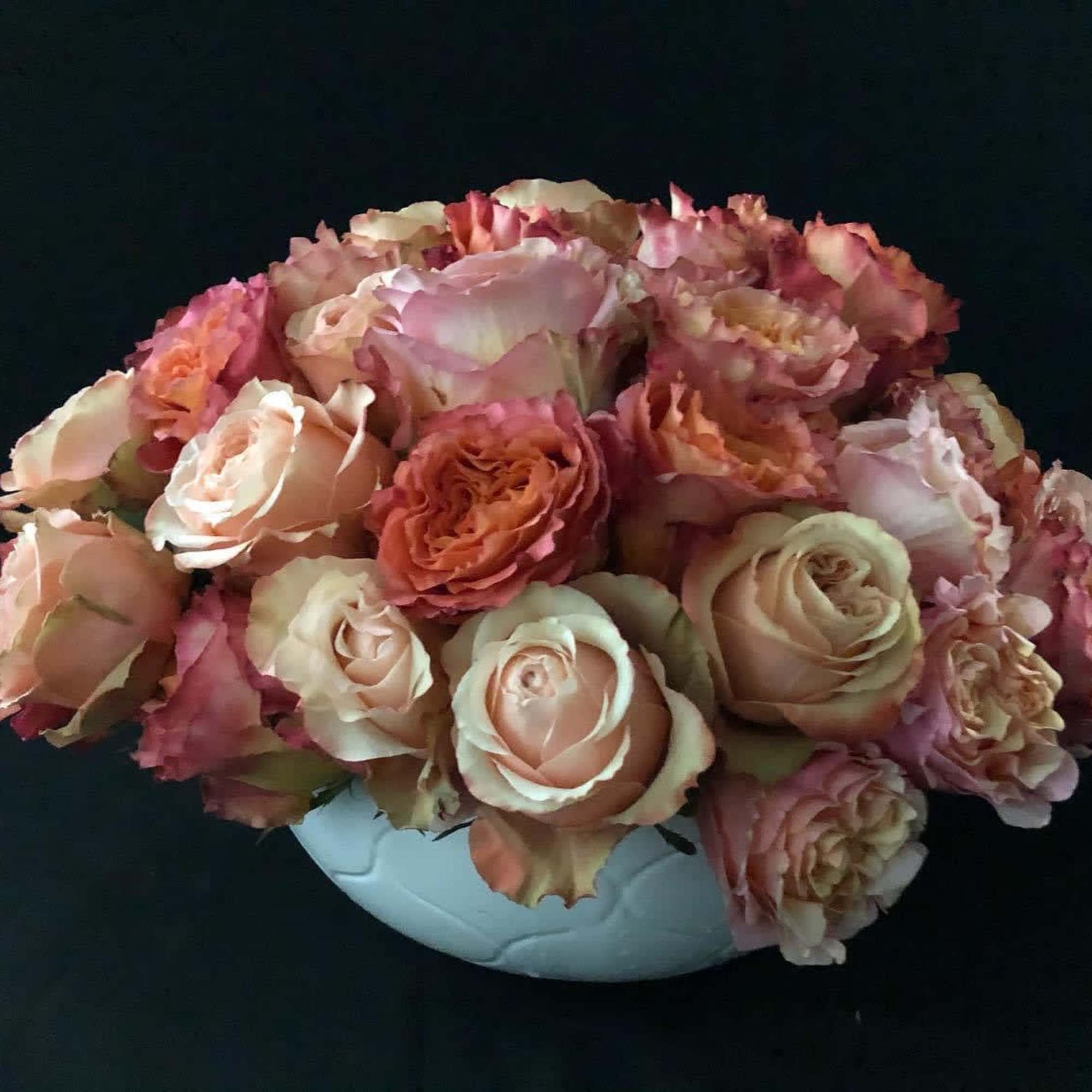Pink and peach roses arranged in a white vase