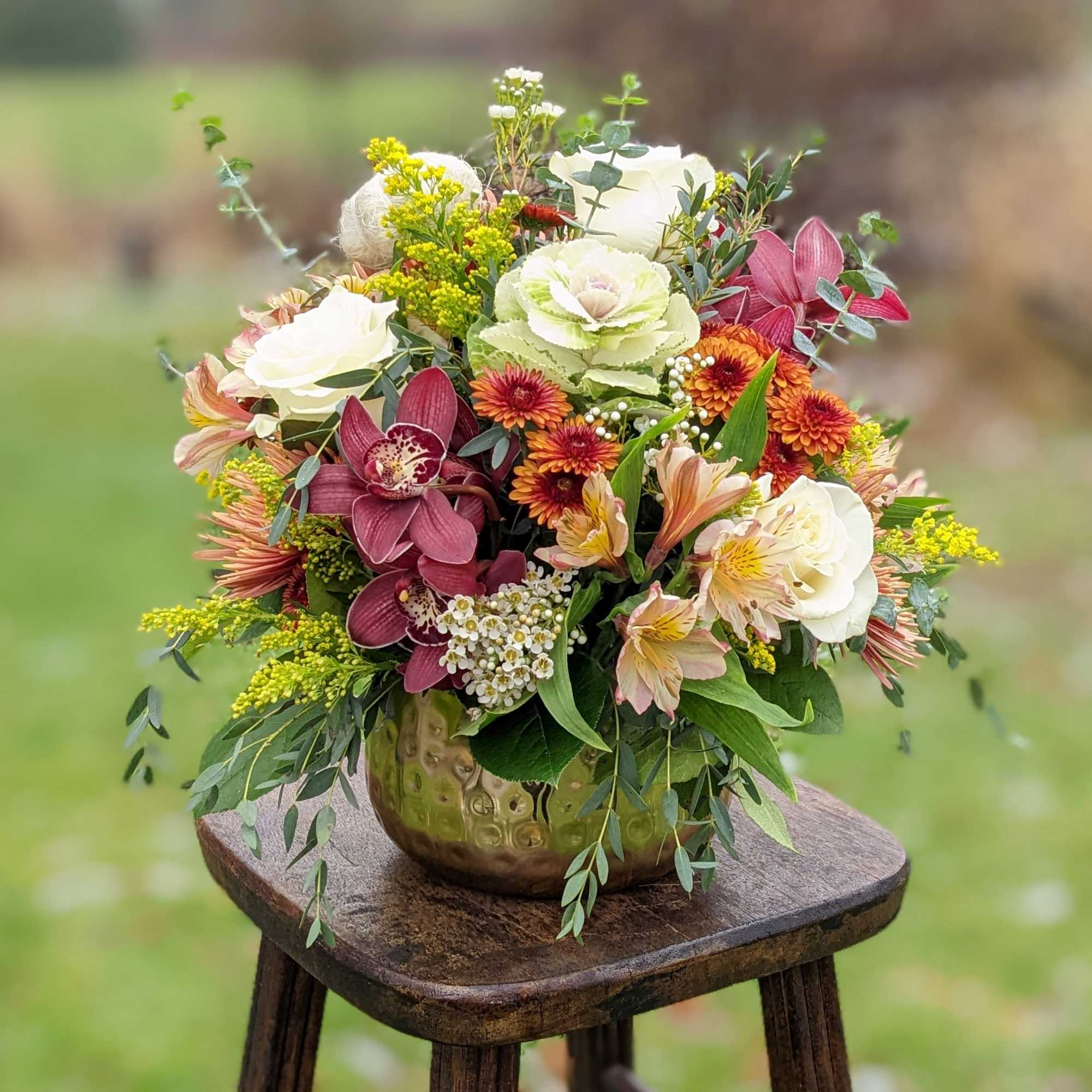 Mixed floral arrangement in a gold vase with white, pink, and orange blooms