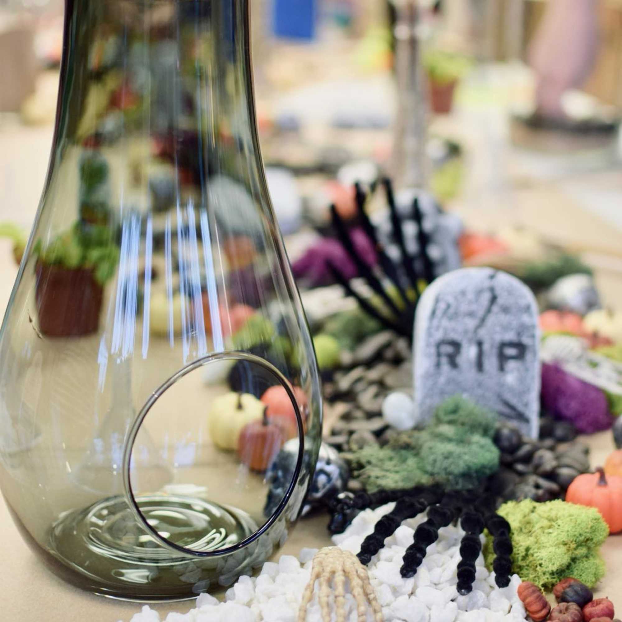 Glass vase with Halloween graveyard decorations and white pebbles