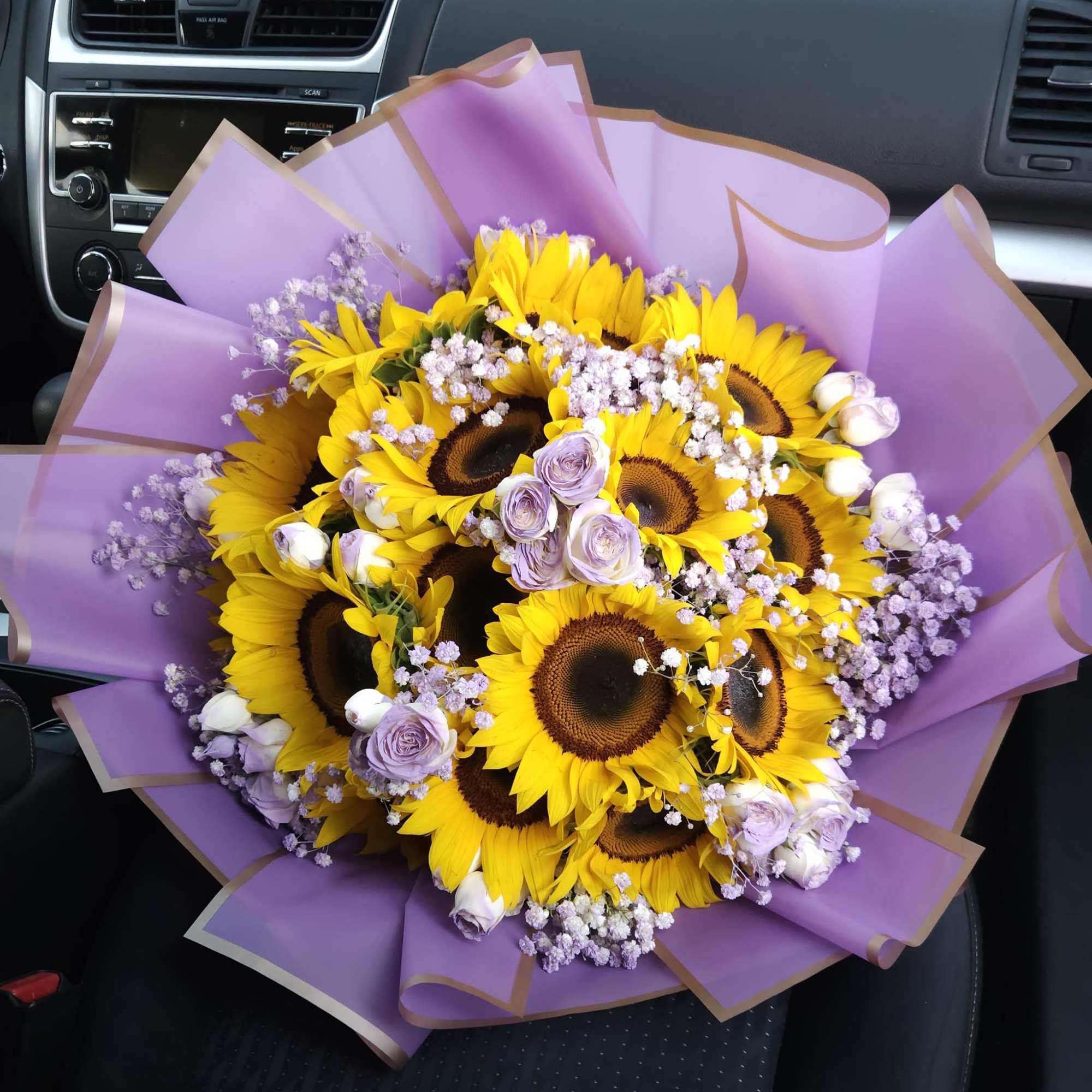 Golden sunflowers, lavender roses and white and lilac baby&rsquo;s breath create a