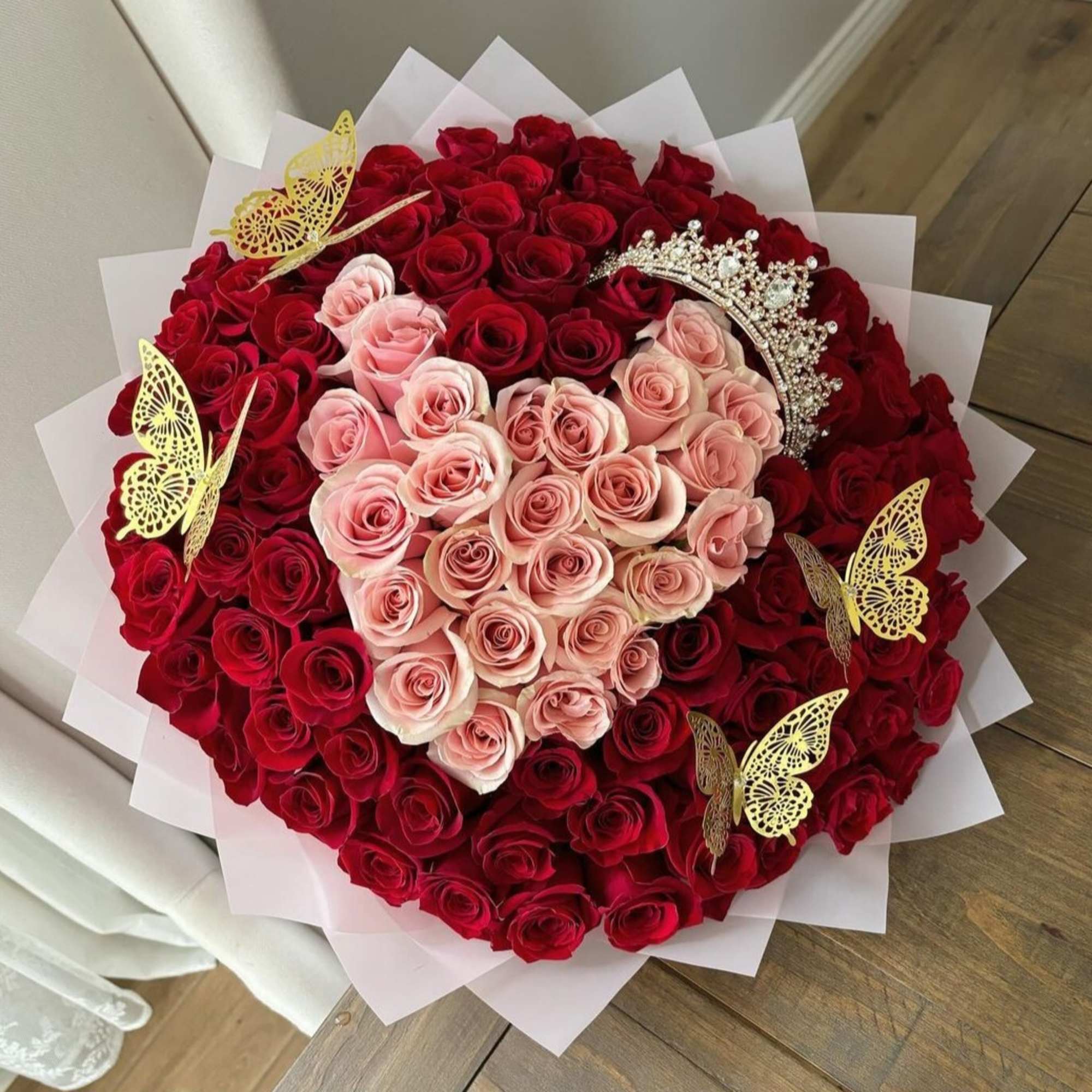 Heart-shaped bouquet of red and pink roses with gold butterfly picks