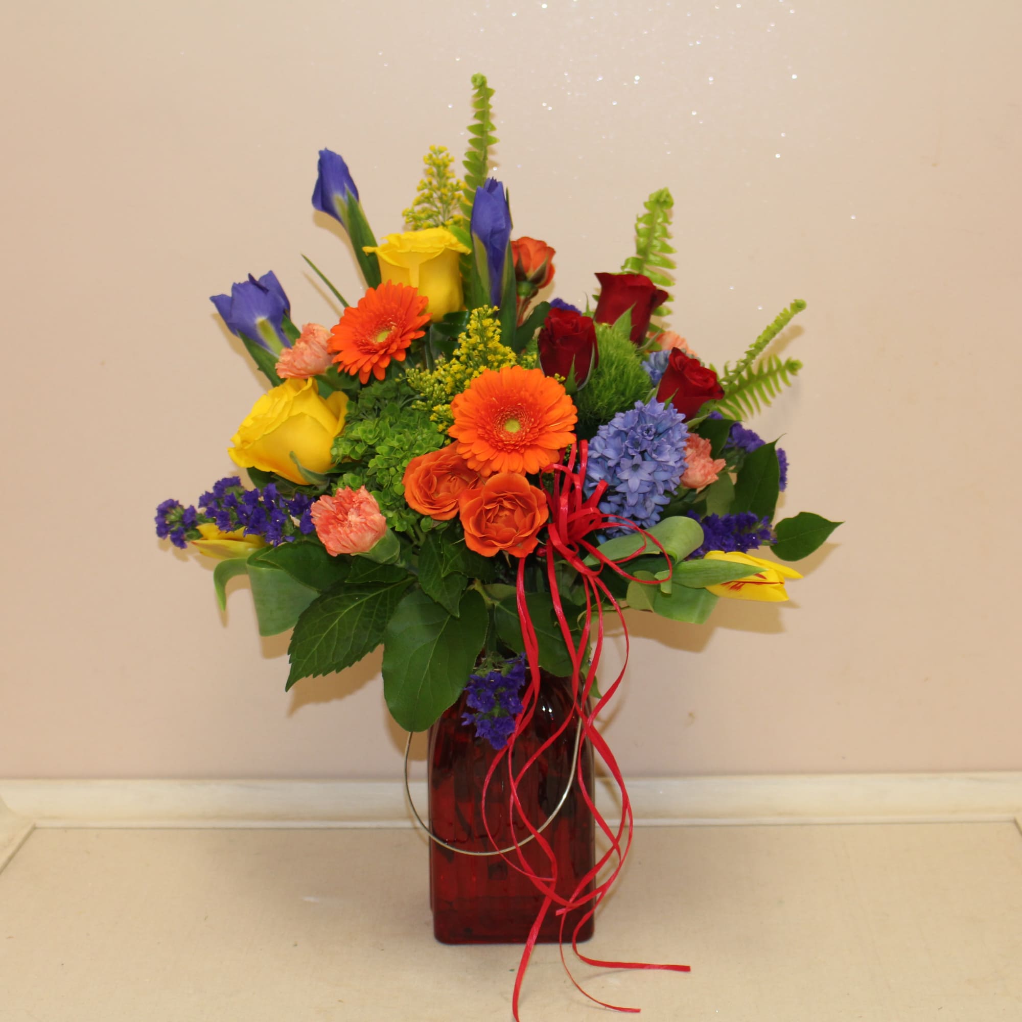 Colorful bouquet in a red glass vase with ribbon