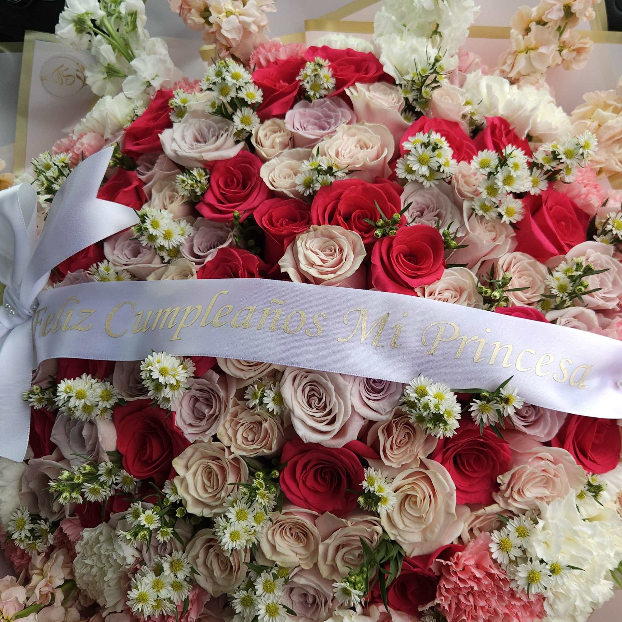 Large bouquet of pink and white roses with small white daisies and a ribbon