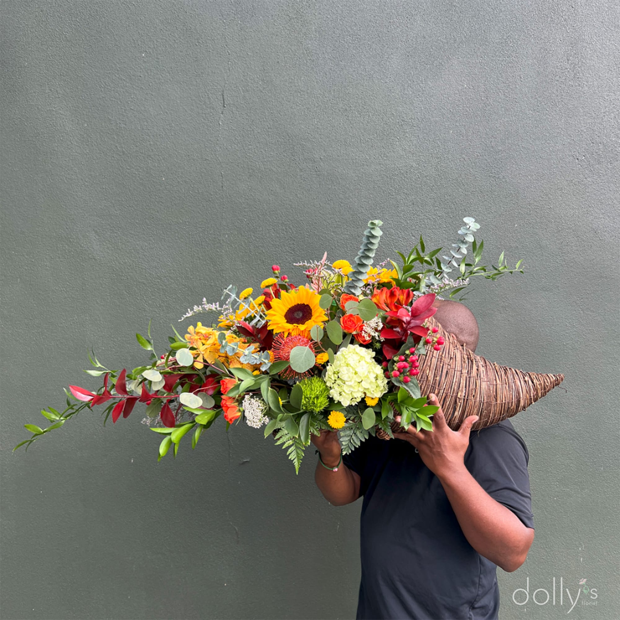 Large mixed bouquet in a woven basket held by a person