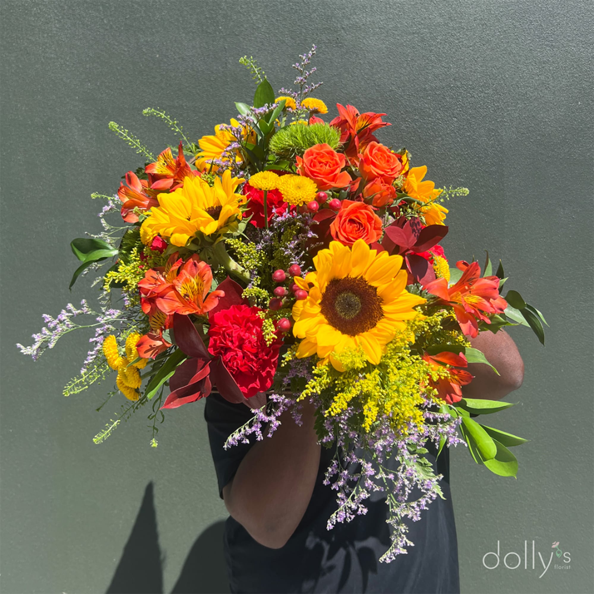 Bright mixed bouquet with sunflowers, orange roses, and red blooms