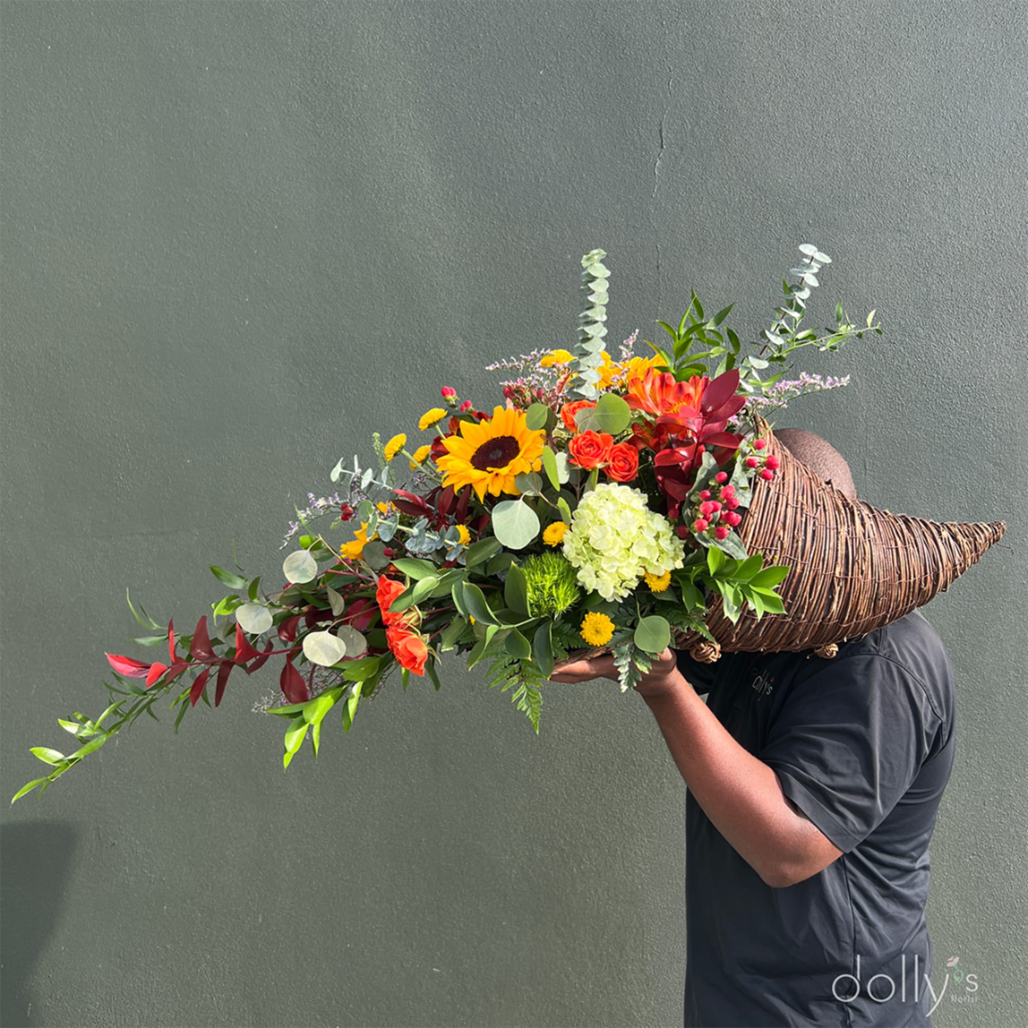 Large mixed bouquet in a woven horn-shaped basket held by a person
