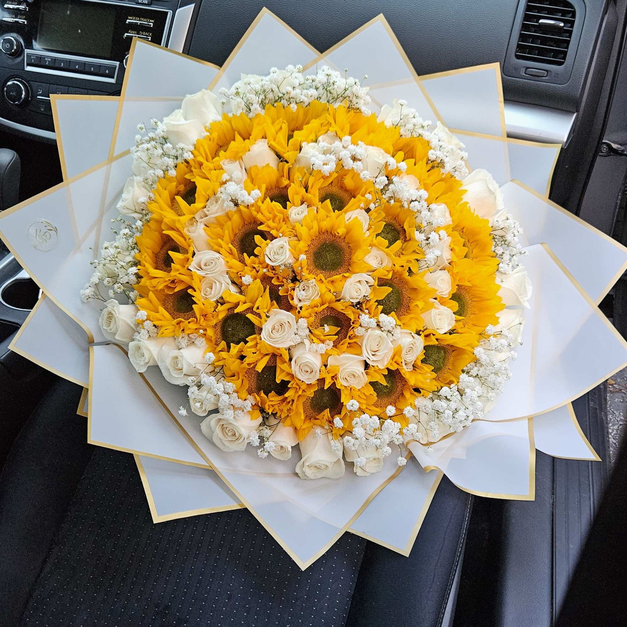 Bouquet of yellow sunflowers and white roses wrapped in white paper