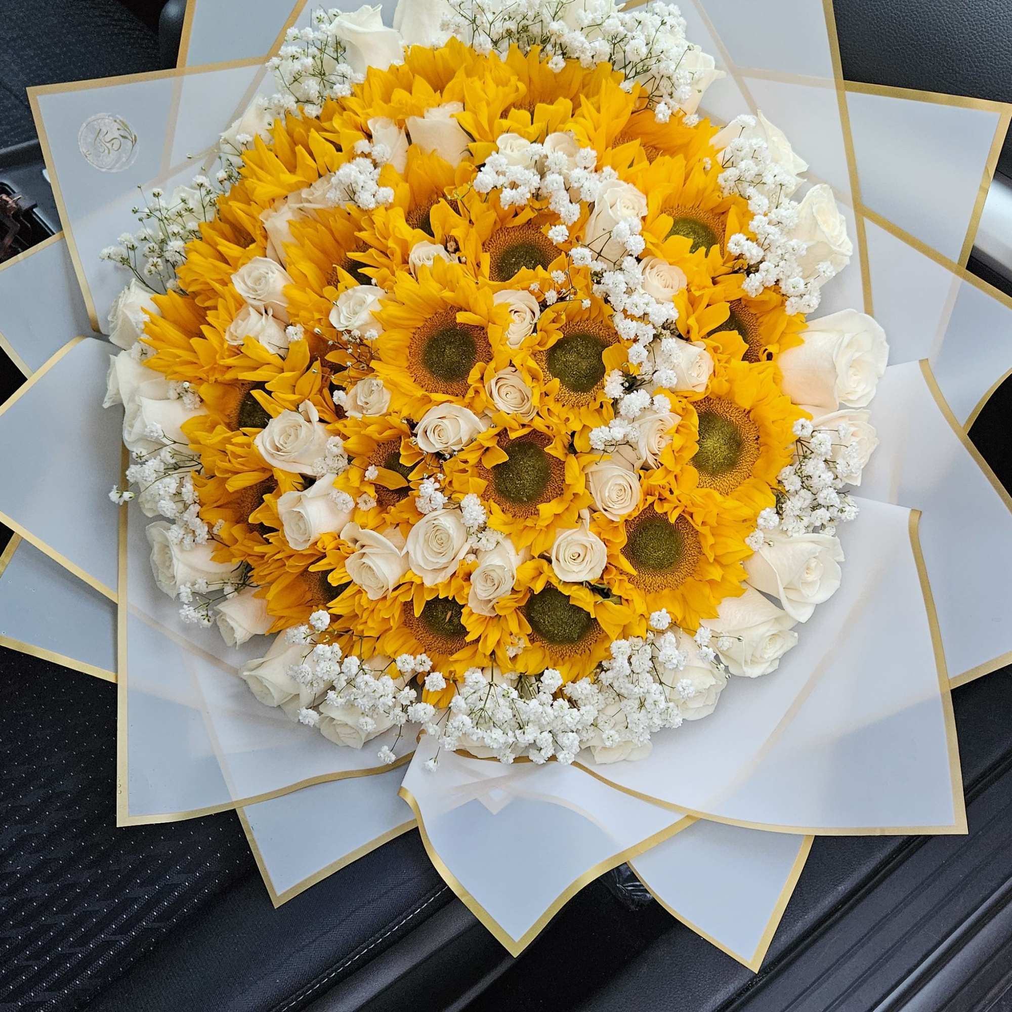 Large bouquet of sunflowers and white roses wrapped in white paper