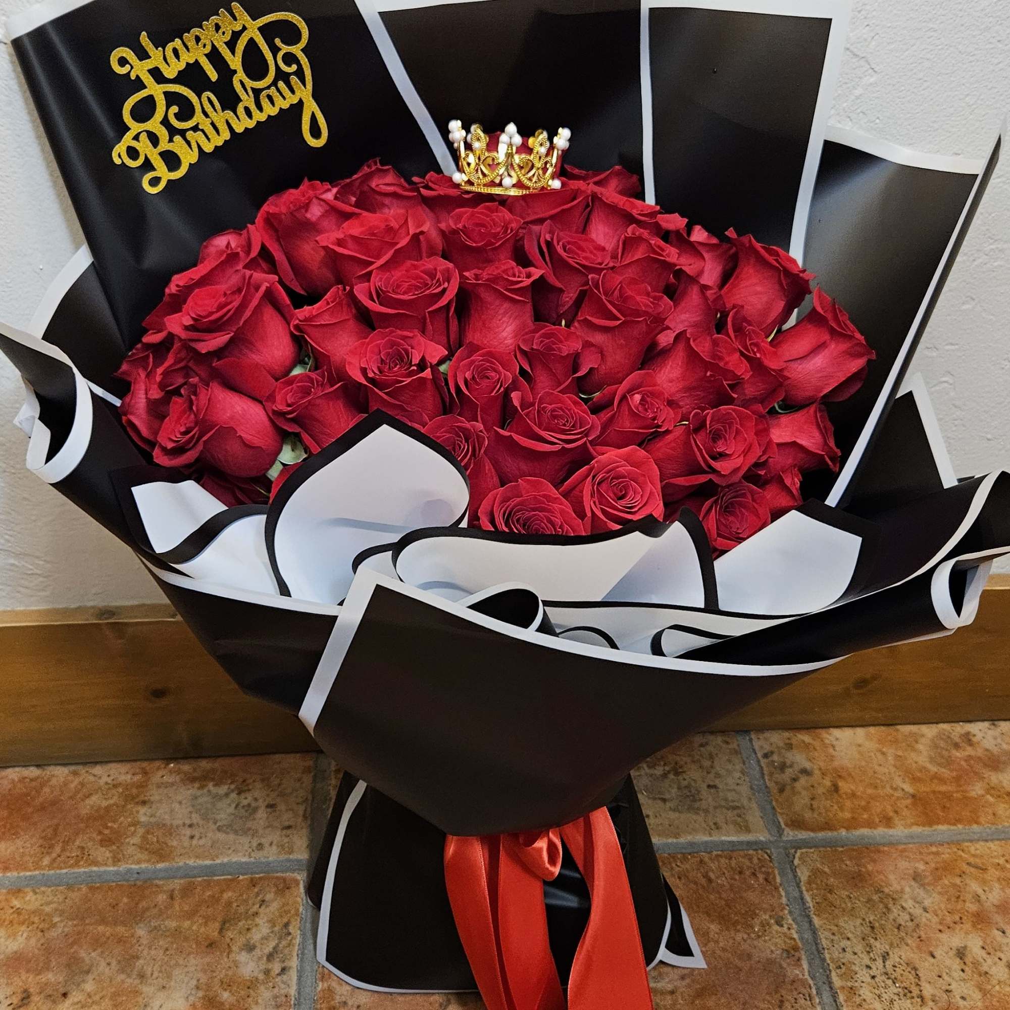 Bouquet of red roses in black and white wrap with a birthday topper