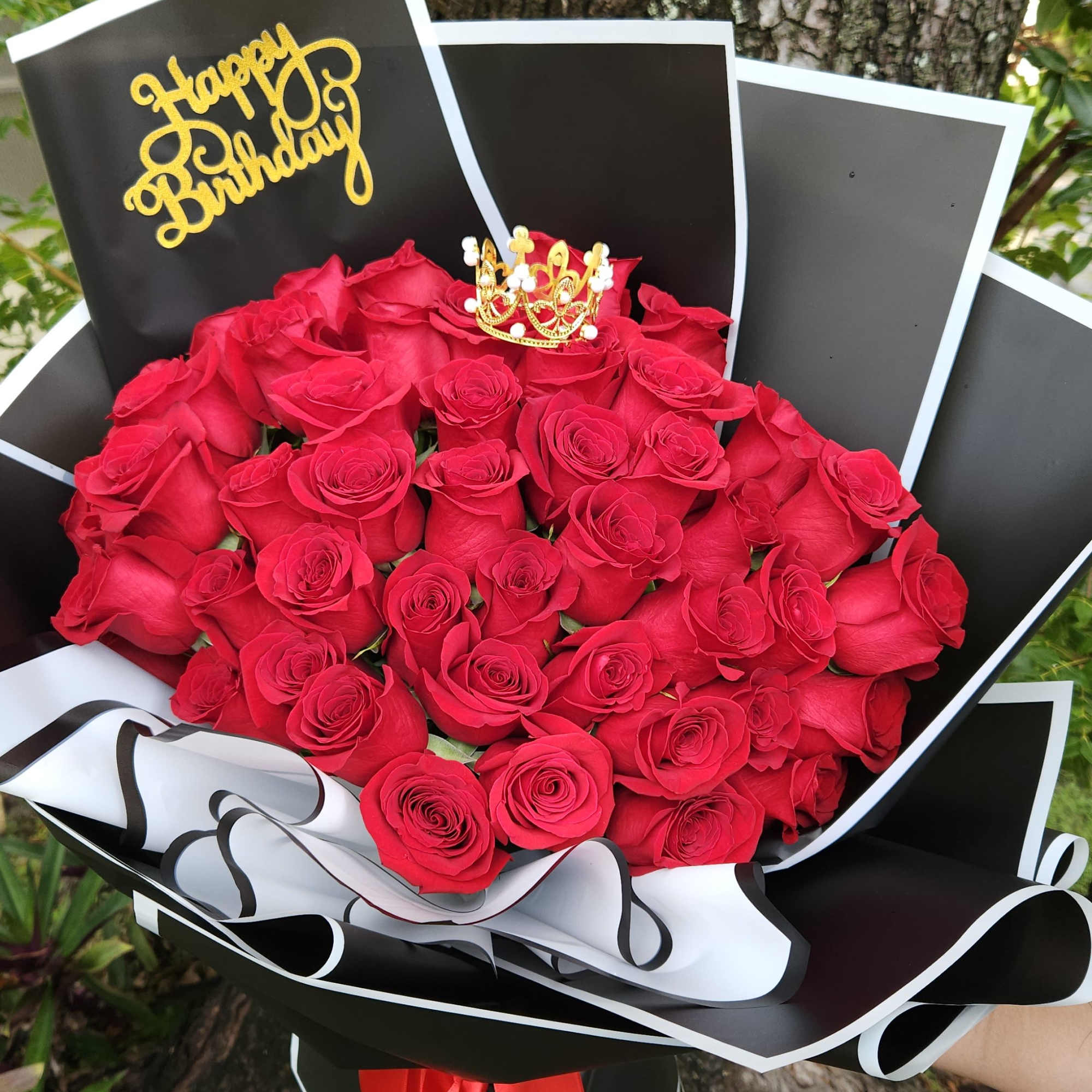Bouquet of red roses with a Happy Birthday topper and black-and-white wrap