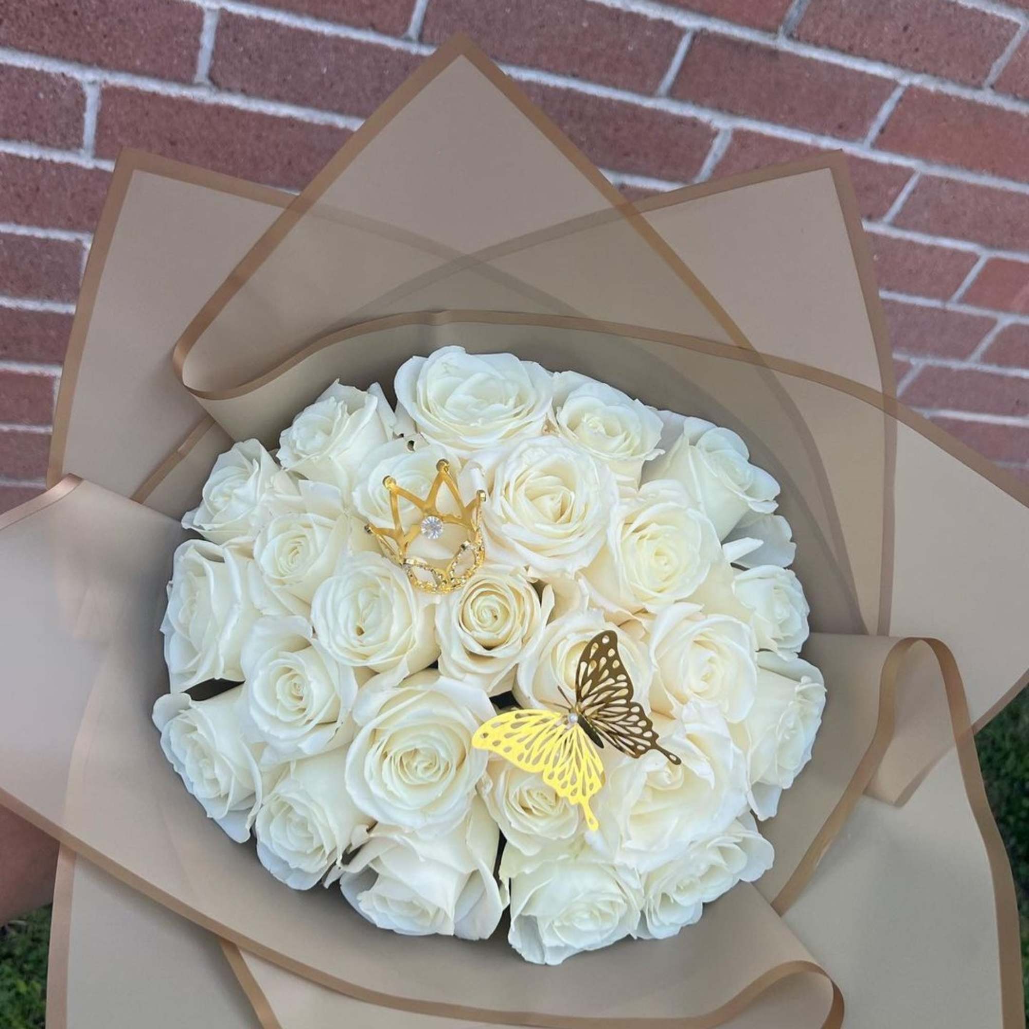 Bouquet of white roses wrapped in tan paper with gold butterfly picks