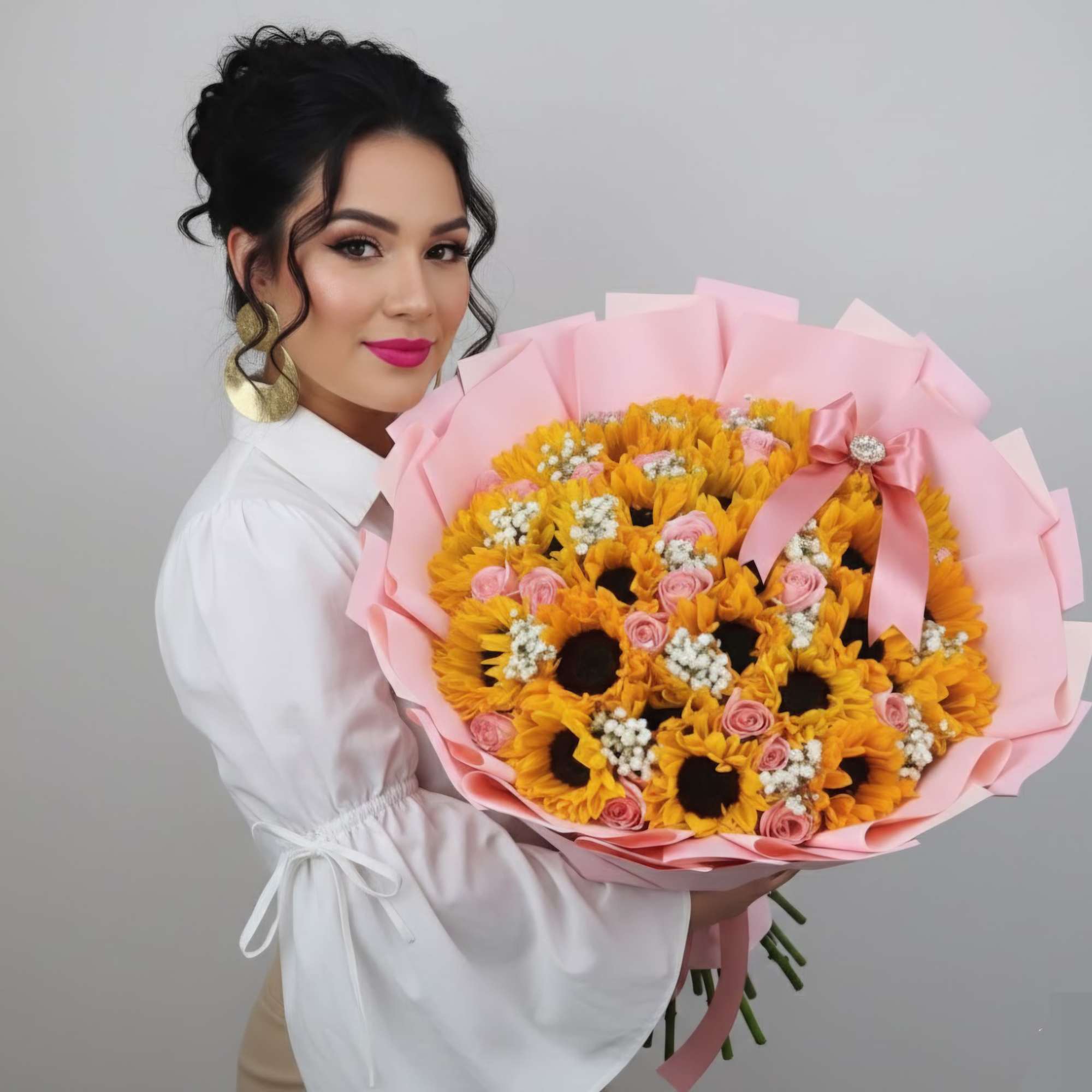 Woman holding a large bouquet of yellow sunflowers and pink roses wrapped in pink paper