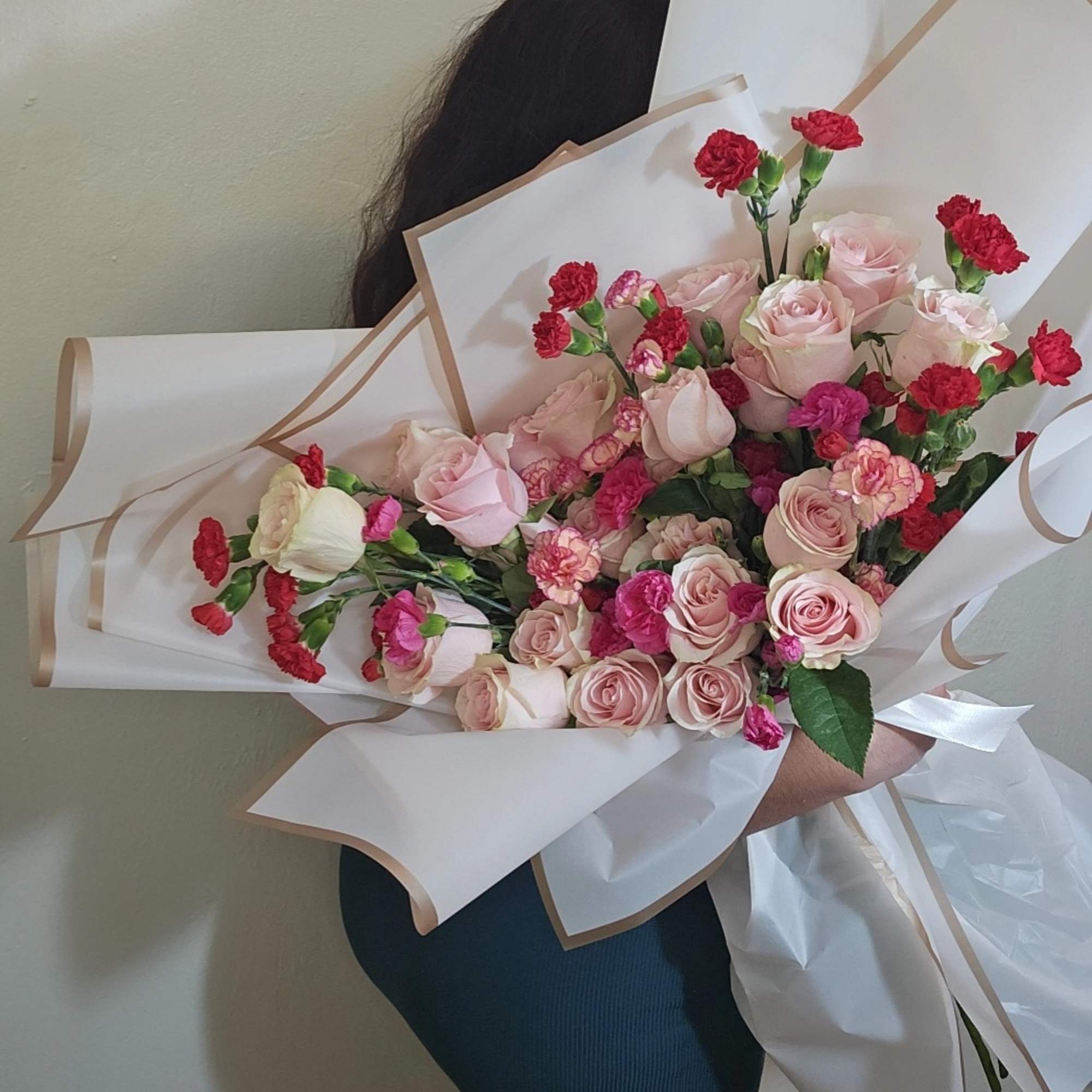 Bouquet of pink roses and red carnations wrapped in white paper