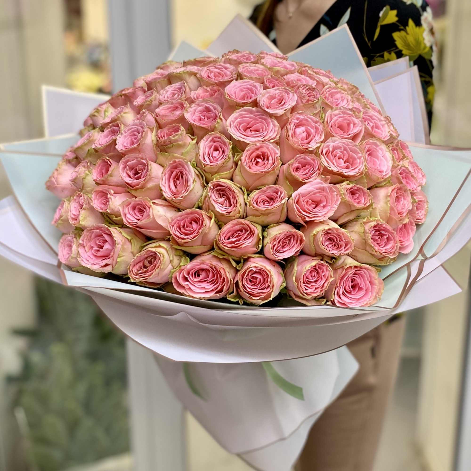 Large bouquet of pink roses wrapped in pale paper