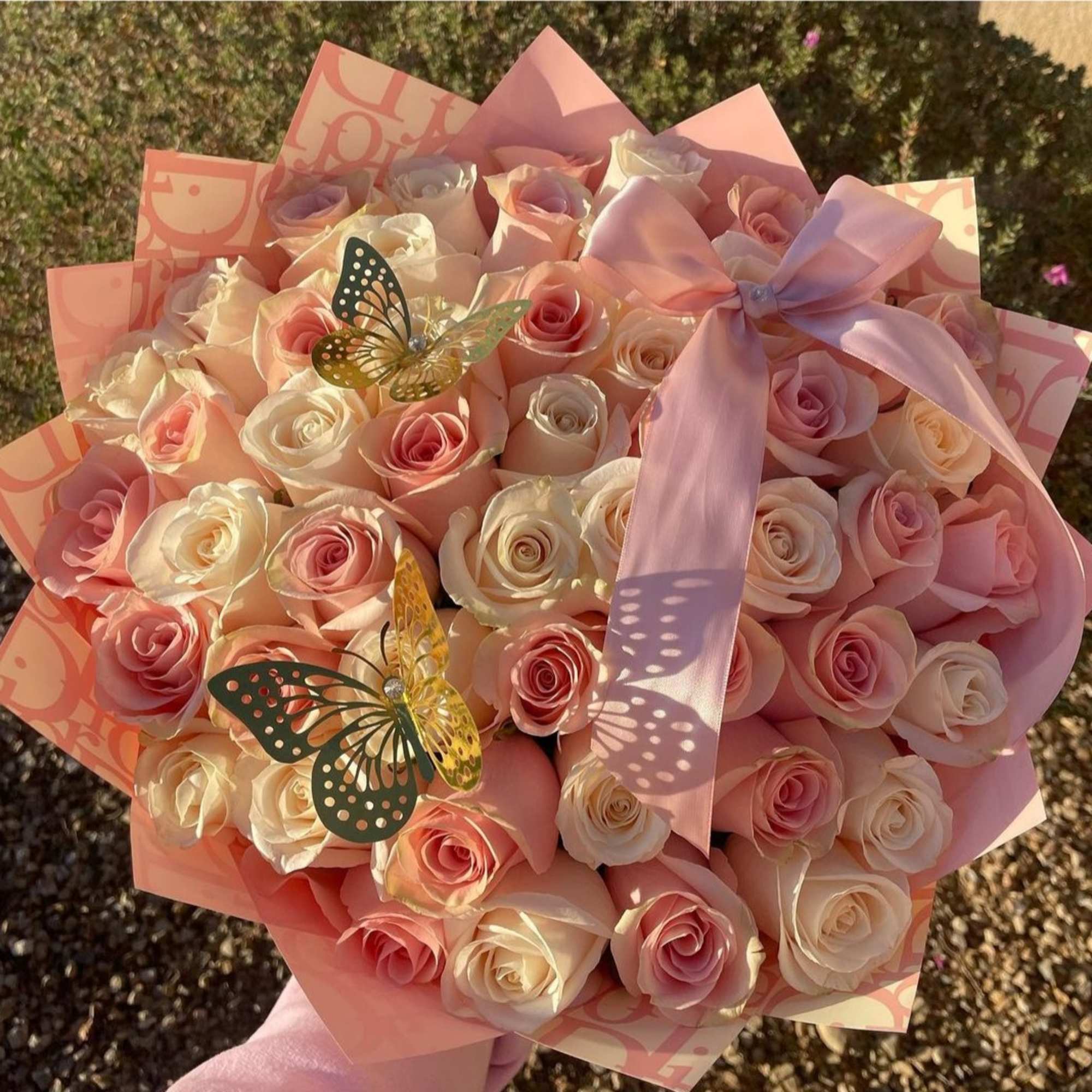 Bouquet of pale pink and cream roses with a pink ribbon and butterfly decorations