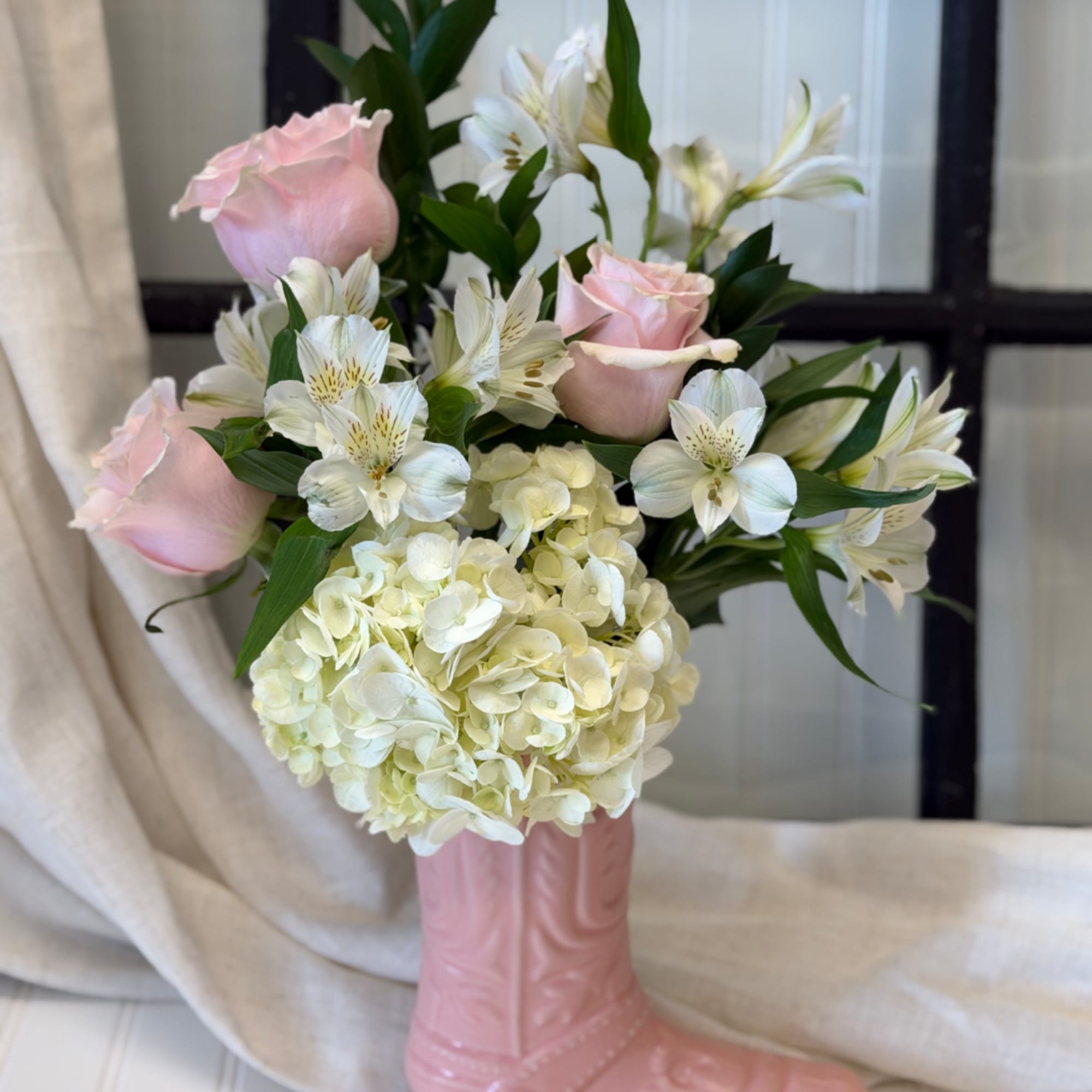 Pink roses and white alstroemeria in a pink boot vase