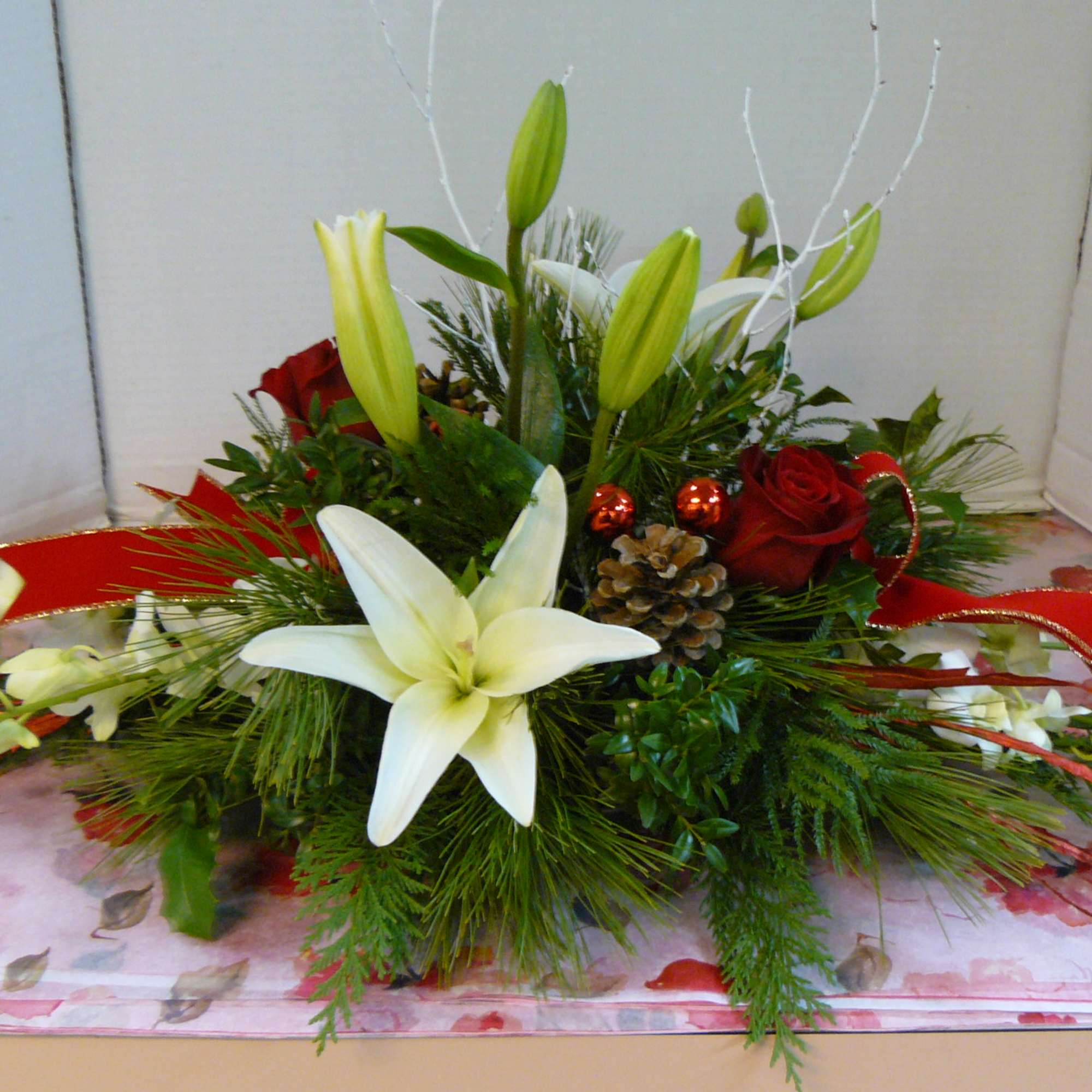 Low floral arrangement with white lilies and red roses on a floral table covering