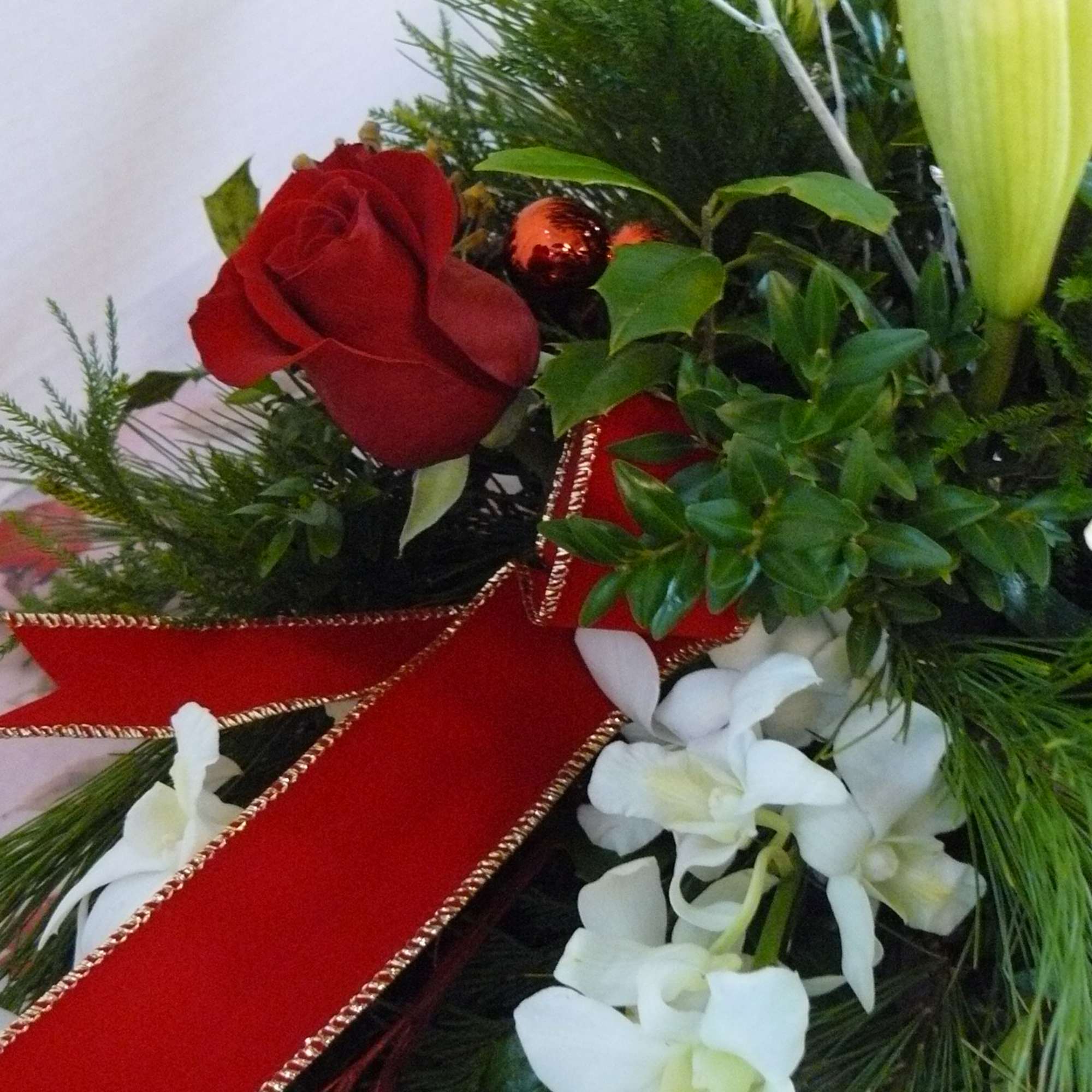 Red rose arrangement with white lilies and a red ribbon