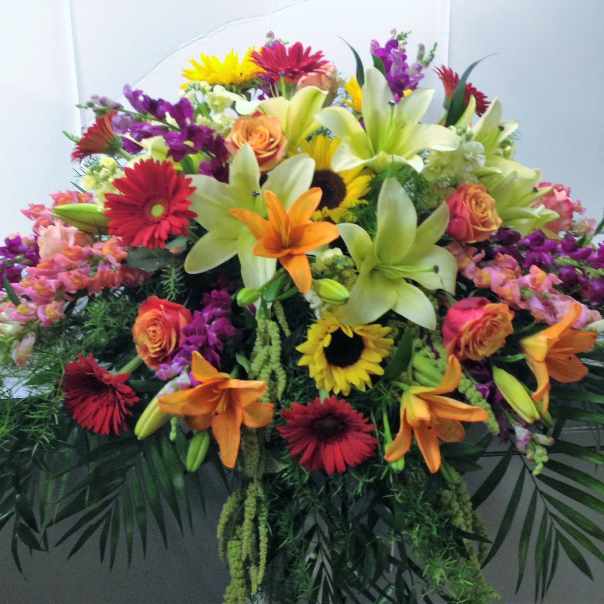 Large mixed floral spray with lilies, roses, gerbera daisies, and sunflowers