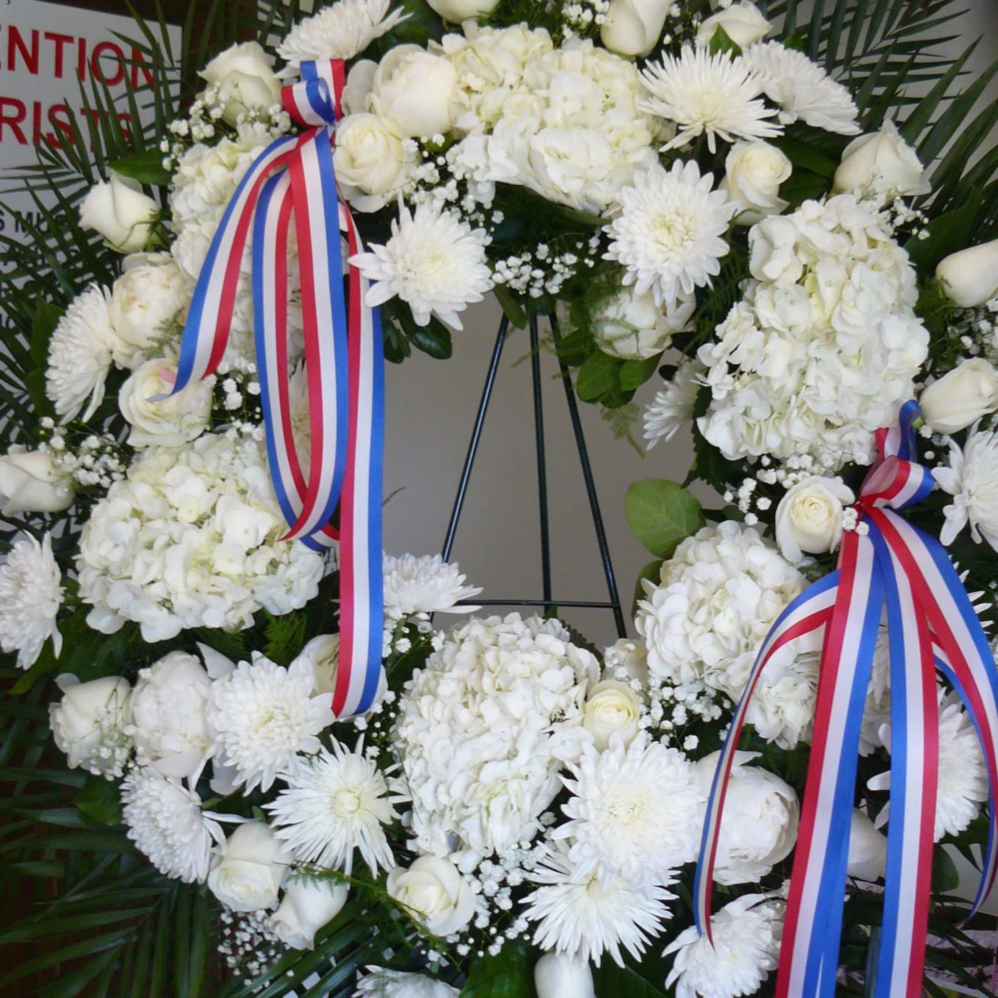 White floral wreath with roses and chrysanthemums on an easel