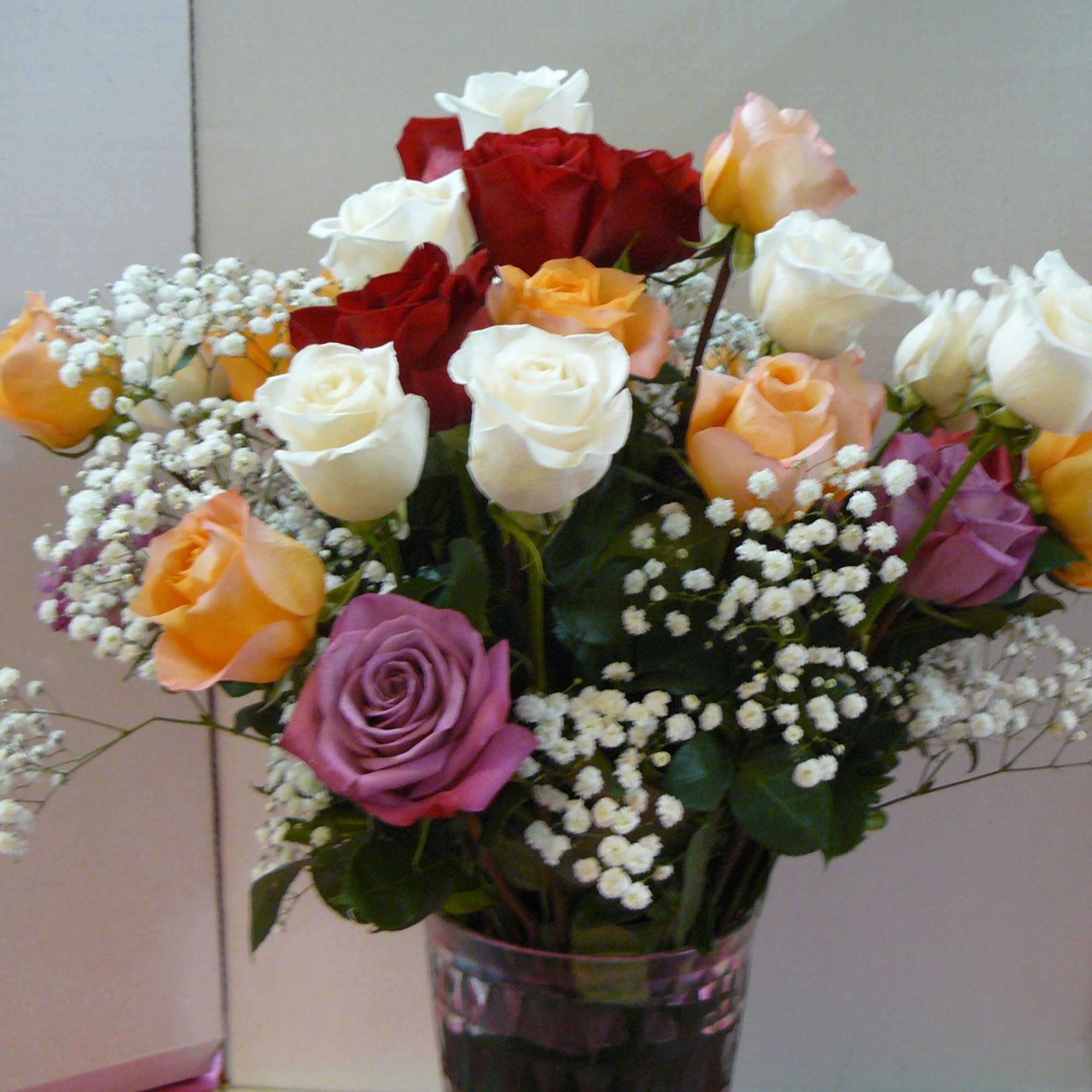 Mixed roses in a clear glass vase with baby's breath