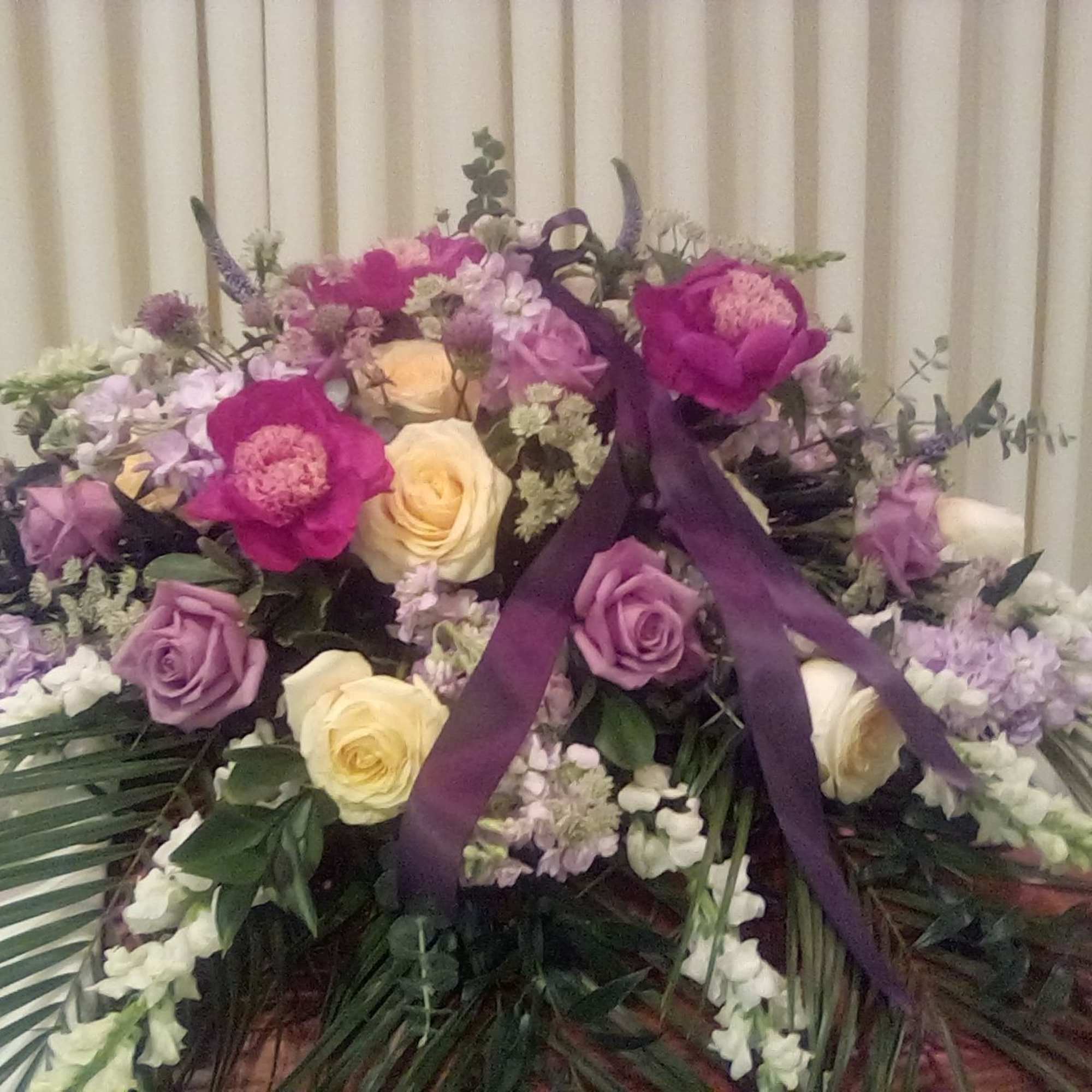 Large bouquet of pink, purple, and cream roses with ribbon