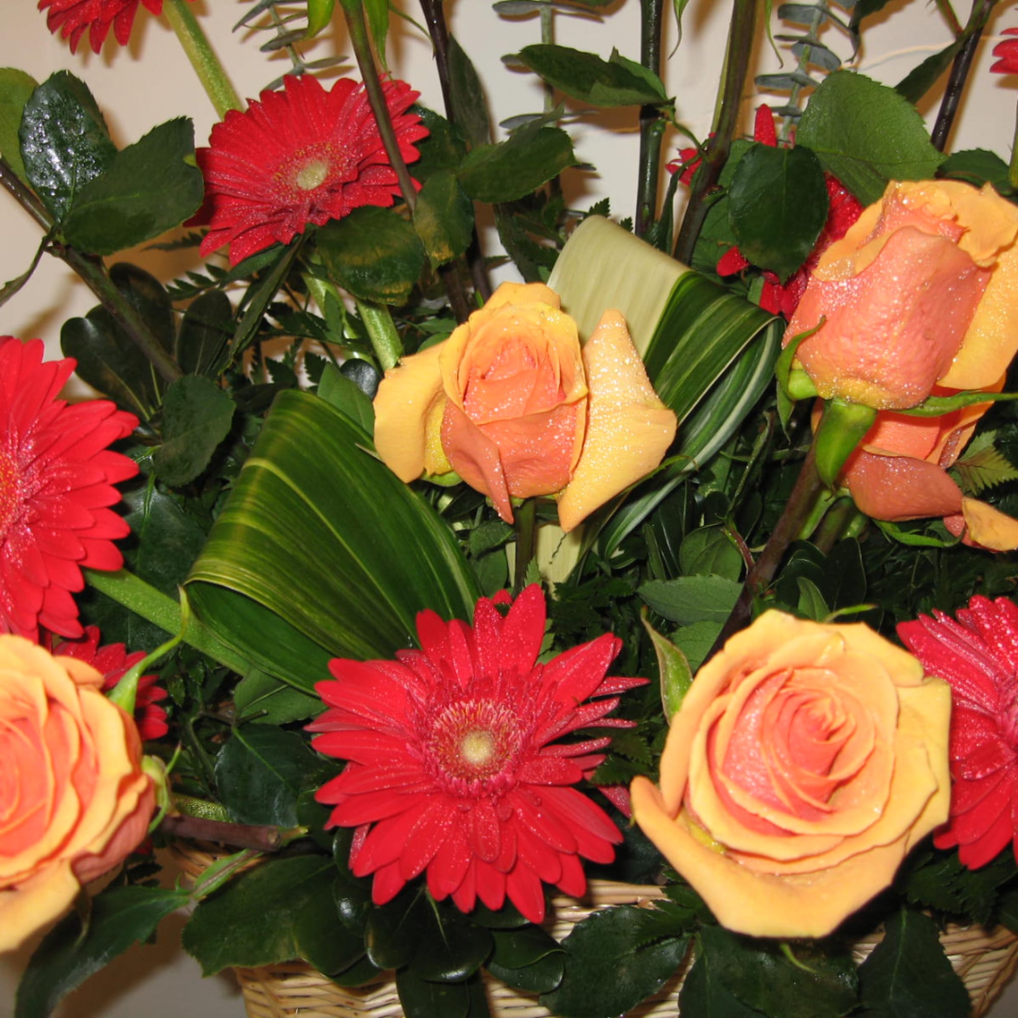 Bouquet of orange roses and red gerbera daisies in a basket