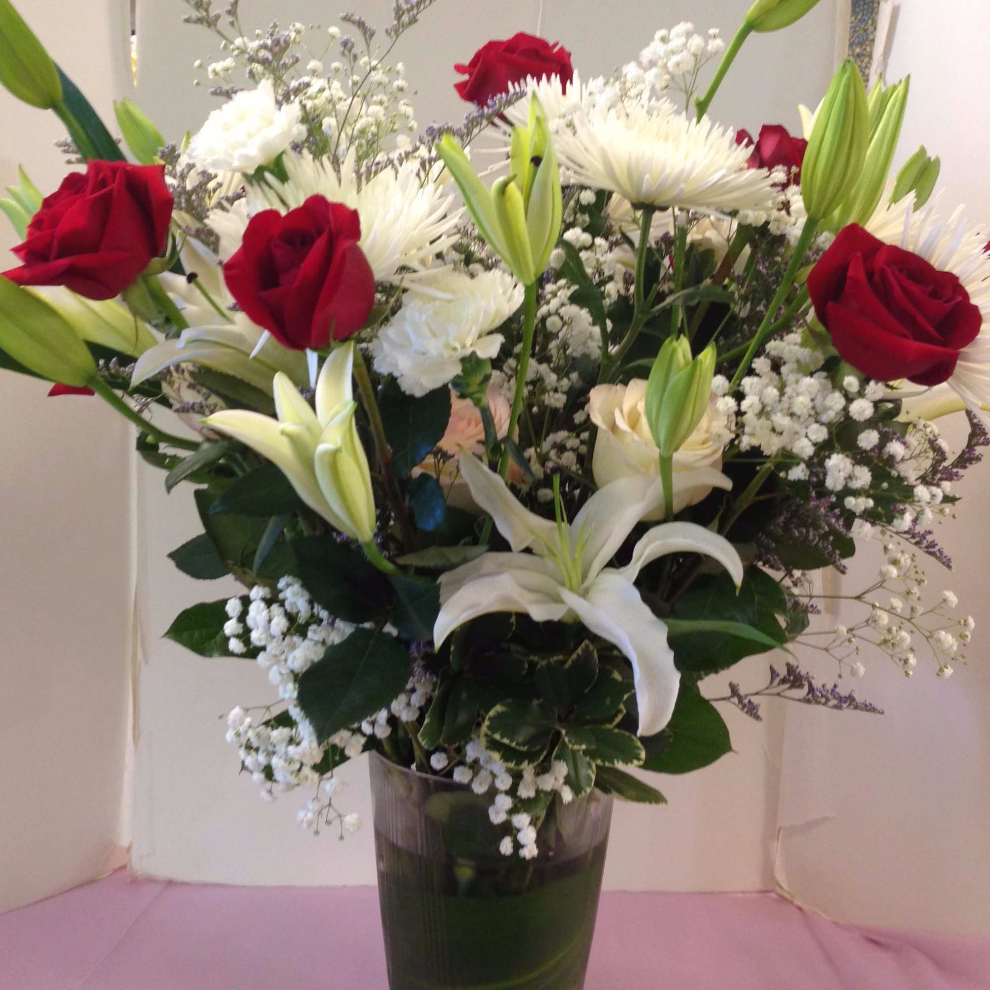 Bouquet of red roses and white lilies in a clear vase