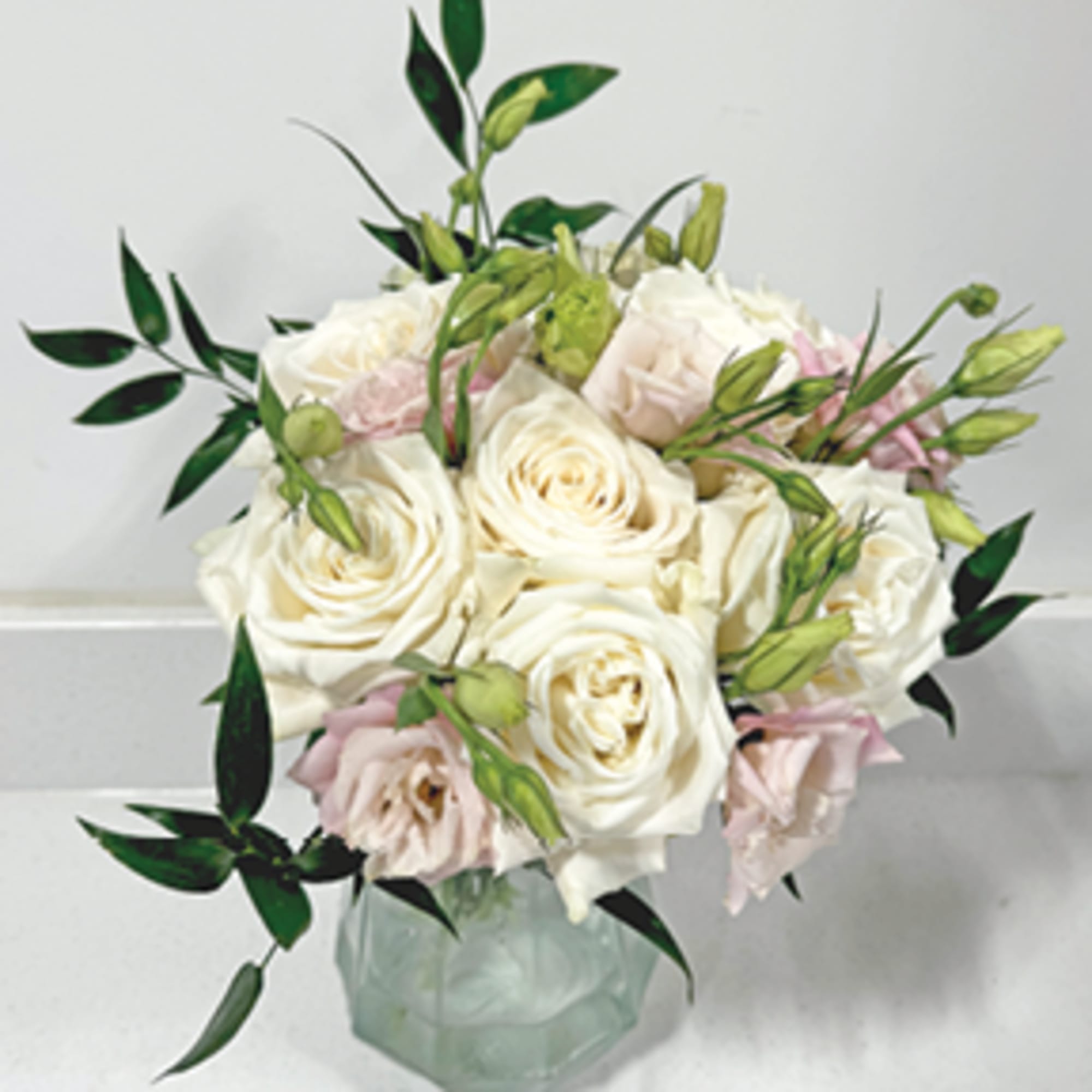 White and blush roses arranged in a glass vase