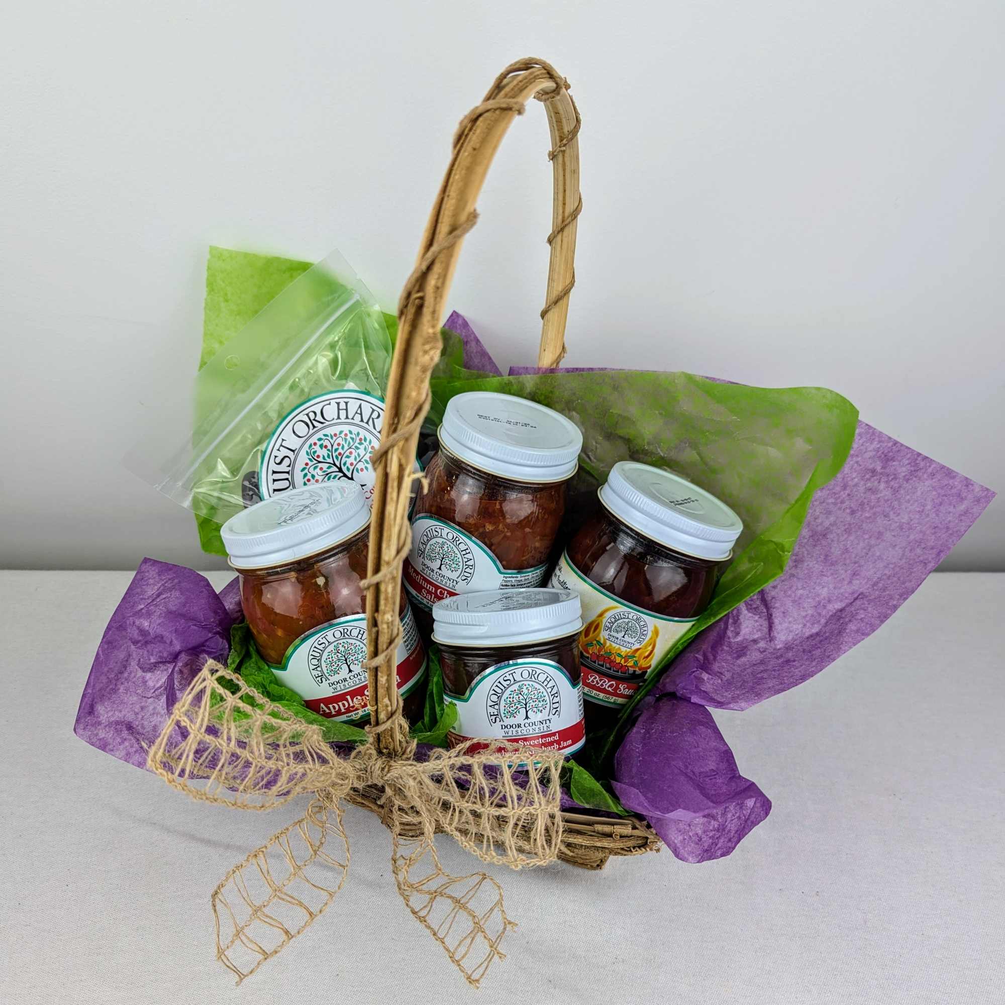 Gift basket with jars of preserves wrapped in purple and green tissue