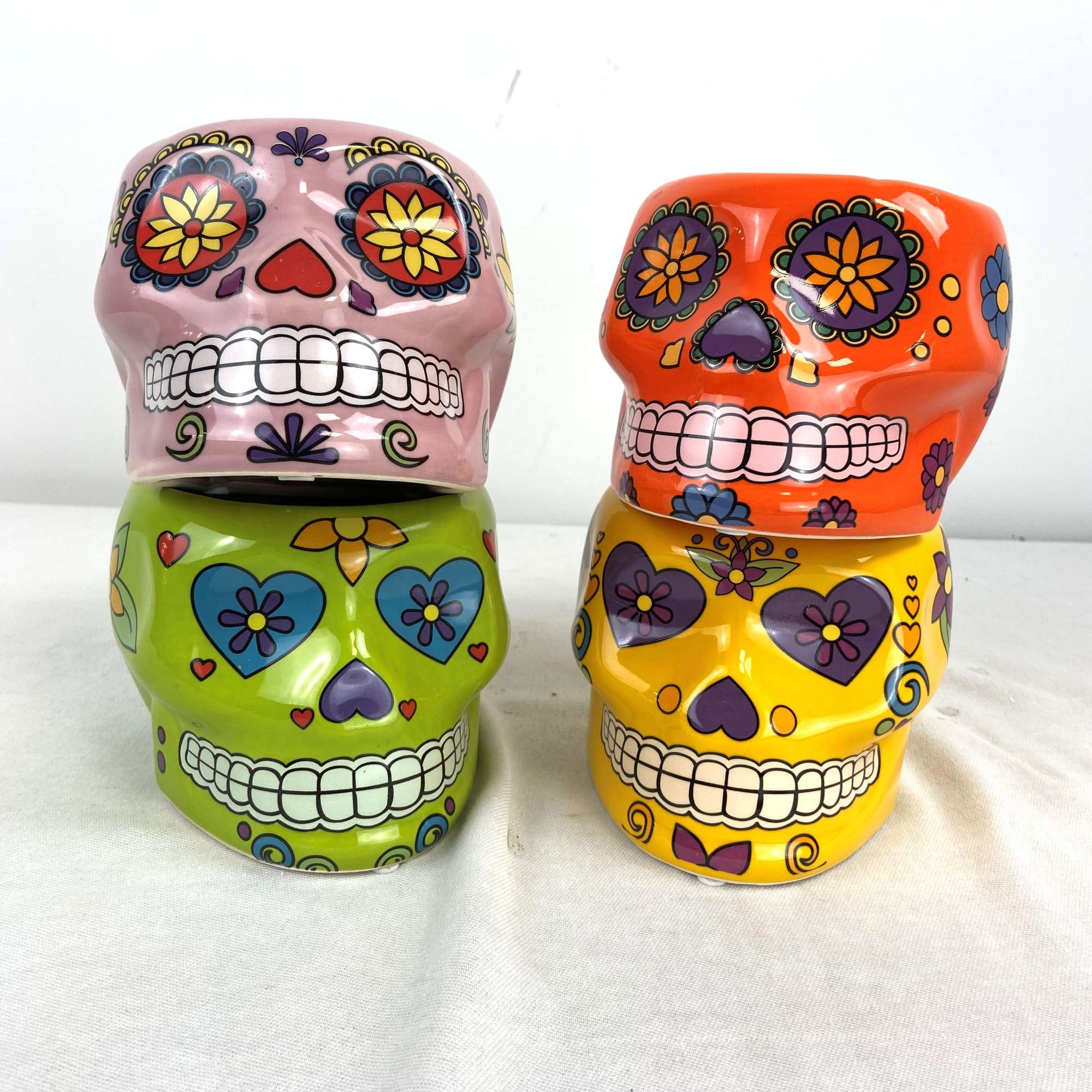 Four colorful sugar skull decorative containers stacked in pairs