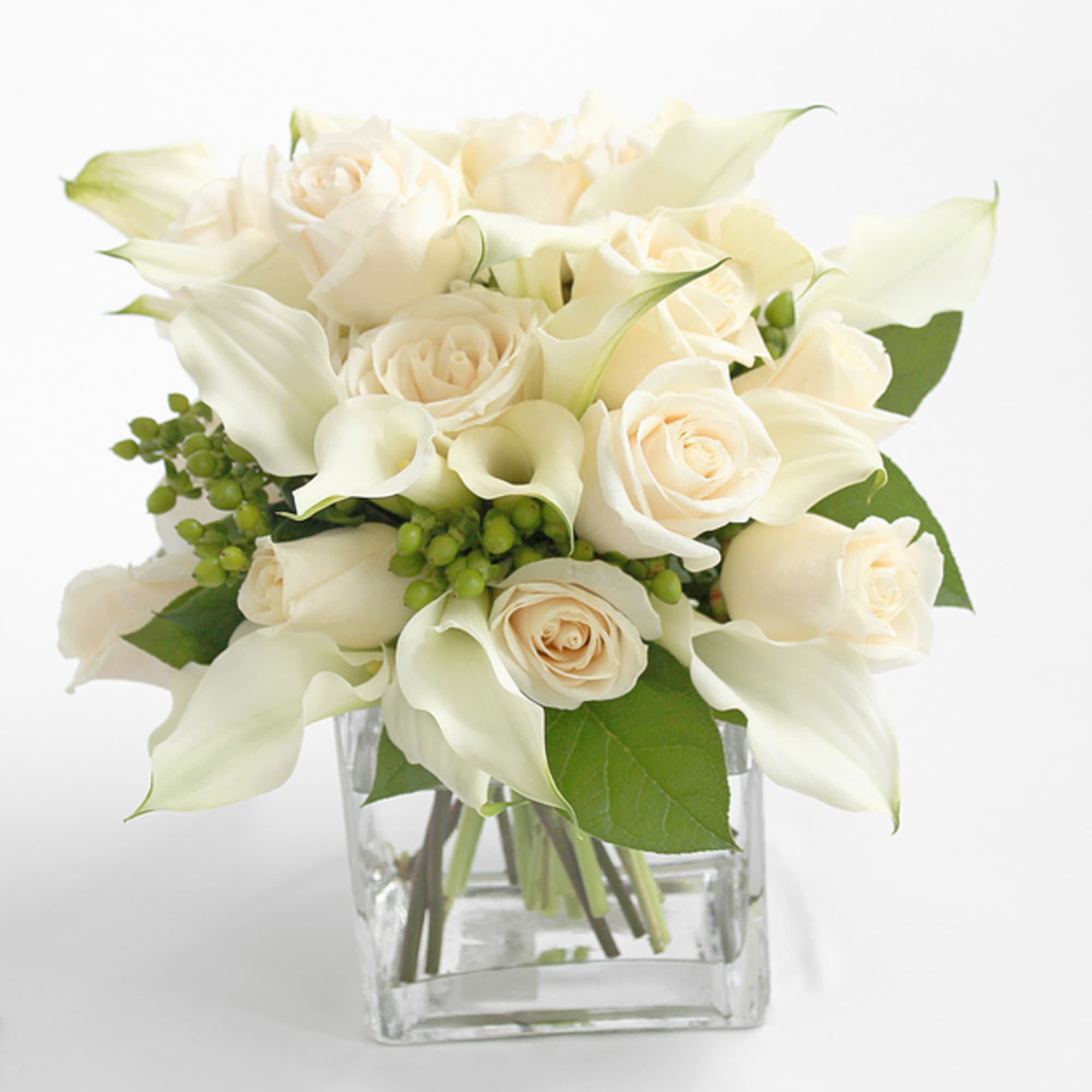 White roses and calla lilies in a clear square vase