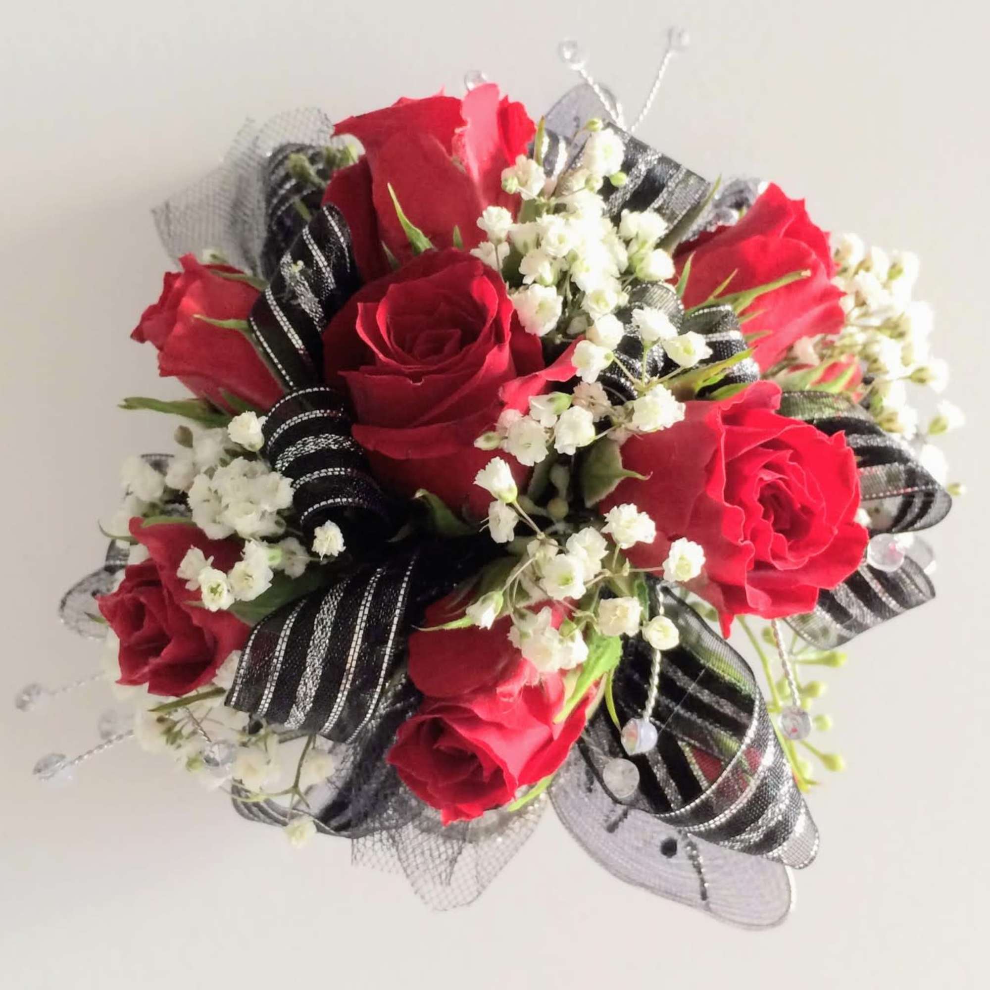 Bouquet of red roses with white filler flowers and black ribbon accents