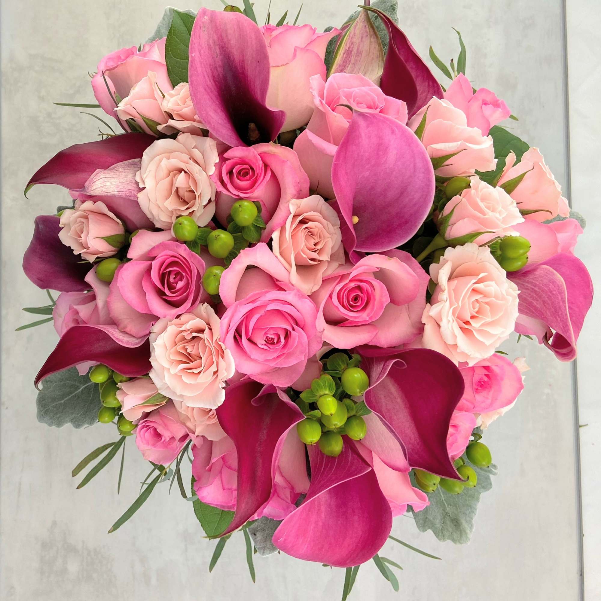 Pink roses and dark magenta calla lilies in a round bouquet